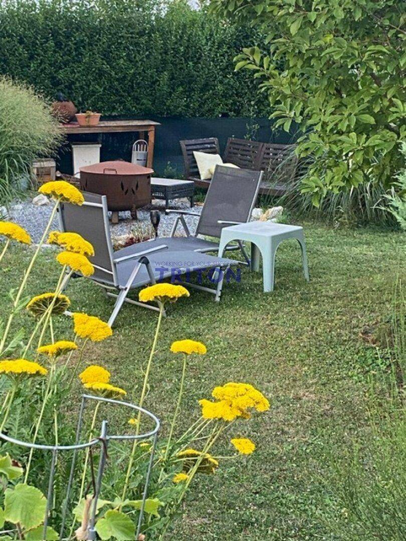 Entspannungsbereich im Garten mit Liegestühlen und blühenden gelben Pflanzen im Vordergrund.