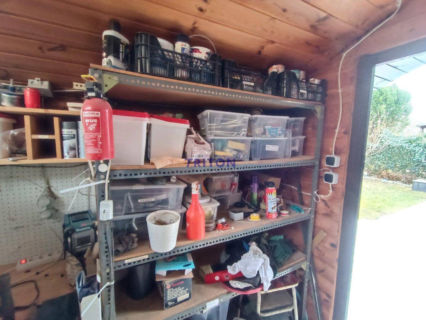 Lagerregale in einem Gartenschuppen, gefüllt mit verschiedenen Utensilien und Behältern.