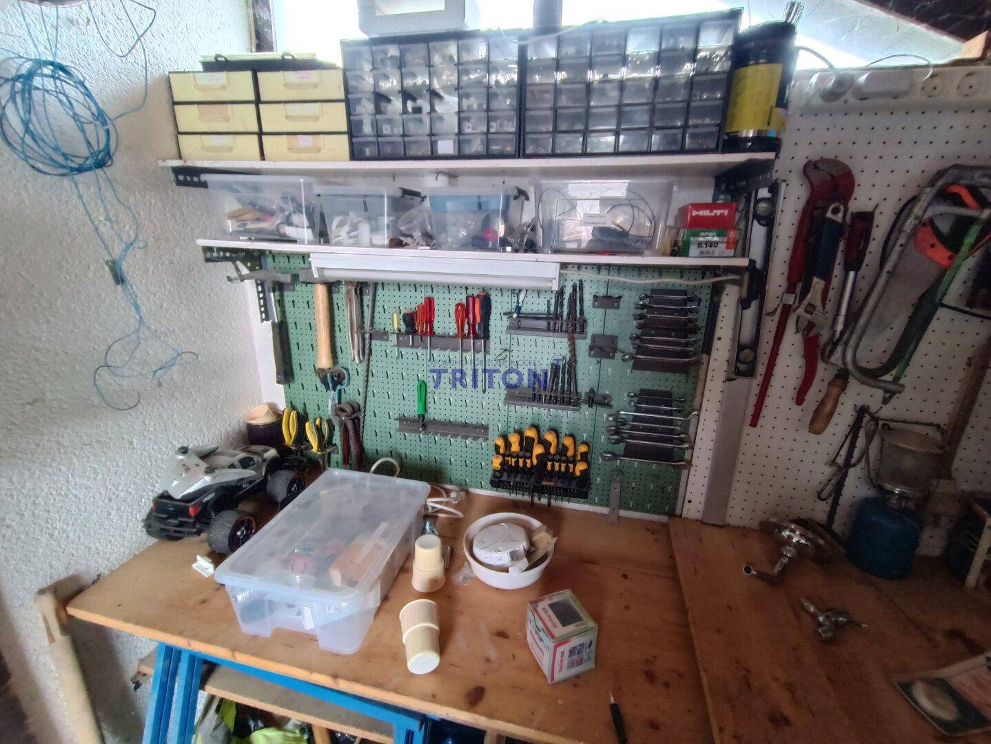 Werkstatt mit Werkbank, Werkzeugwand und verschiedenen Aufbewahrungsboxen.