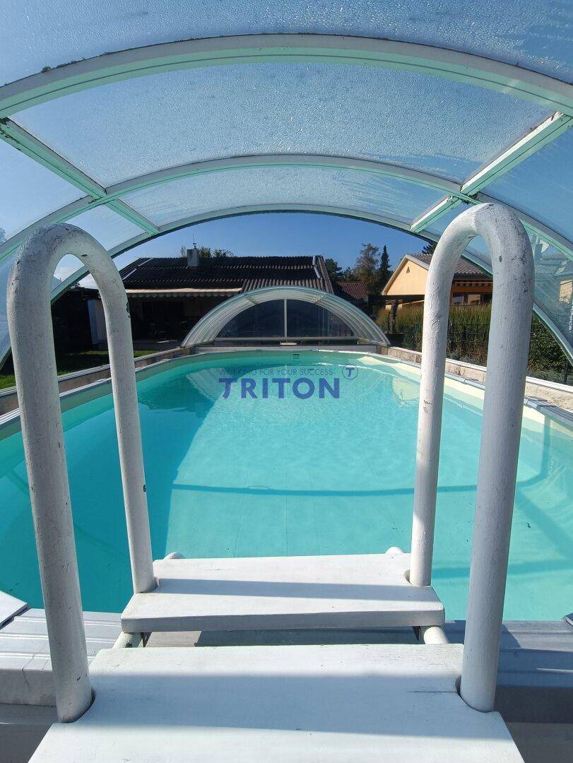 Innenansicht des überdachten Pools mit Einstiegsleiter und Blick auf die Umgebung.