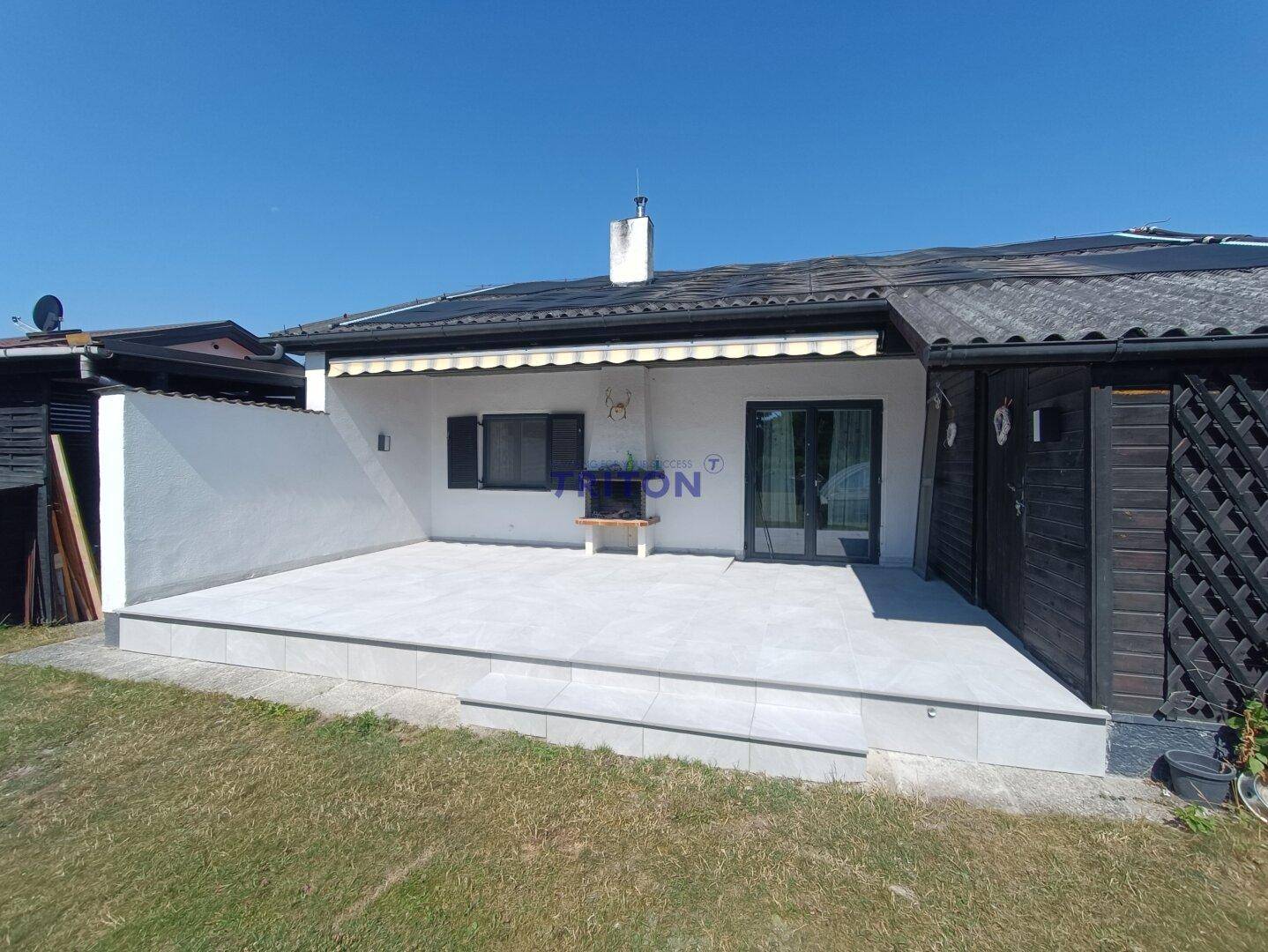 Geräumige Terrasse mit Fliesenboden und direktem Zugang zum Garten, ideal für Grillabende.
