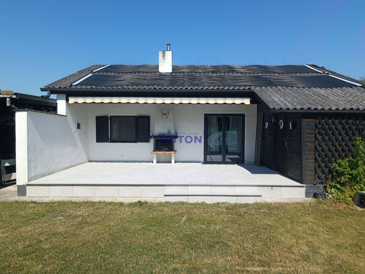 Sonniger Terrassenbereich mit Fliesenboden und Markise, ideal für entspannte Stunden im Freien.