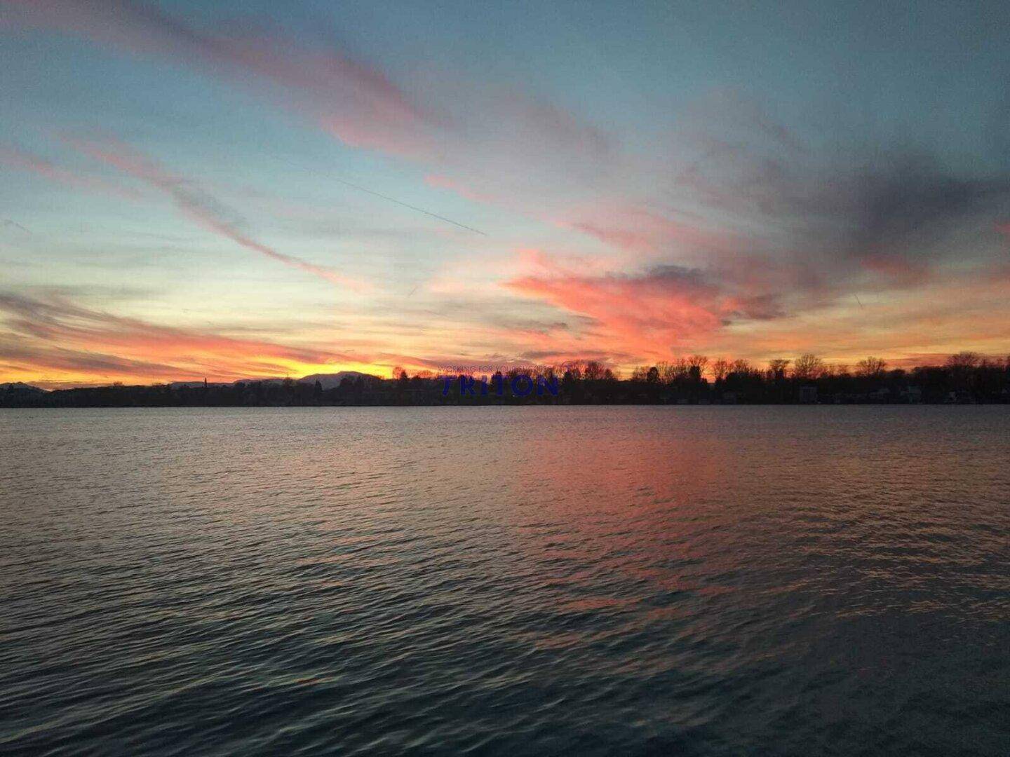 Farbenprächtiger Sonnenuntergang über dem See mit weitem Blick auf die Uferlinie.