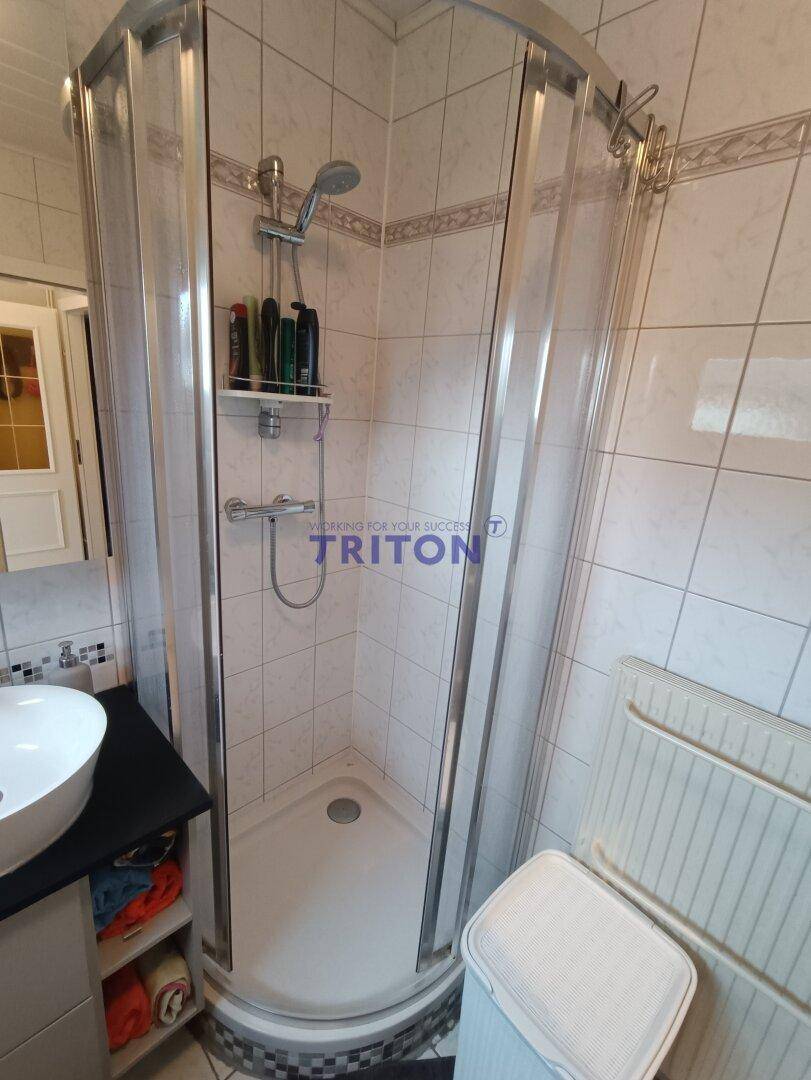 Badezimmer mit Duschkabine, Fliesen an Wänden und Boden sowie modernem Waschbecken.