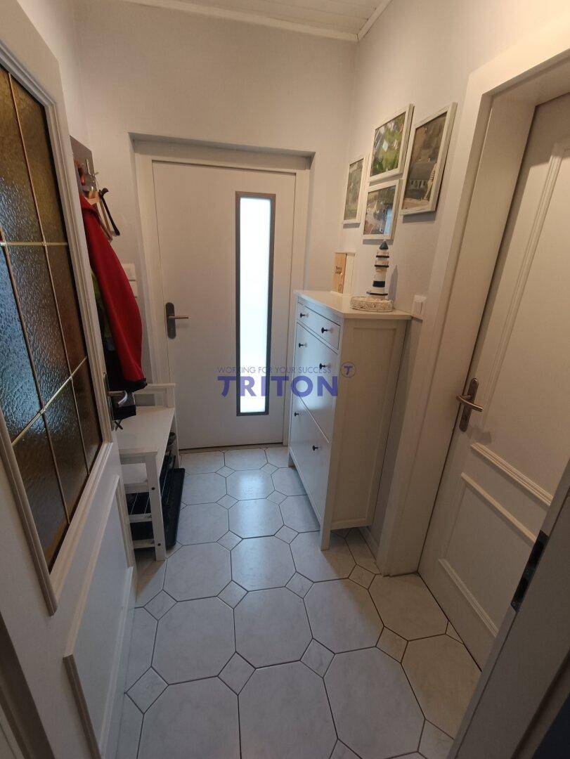 Heller Flur mit geometrischen Fliesen, Schuhschrank und Garderobe.