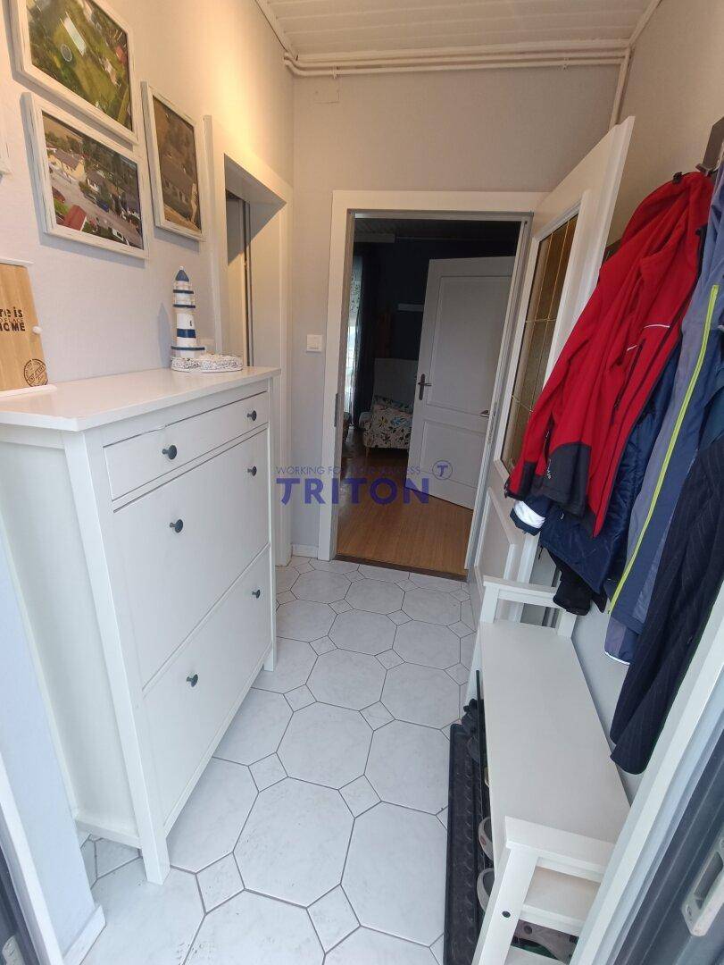 Eingangsbereich mit weißem Schuhschrank, Garderobe und hellen Fliesen.