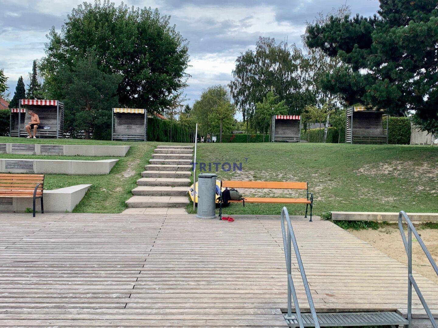 Holzsteg und Treppen zum Seeufer mit Sitzgelegenheiten und Strandkörben.