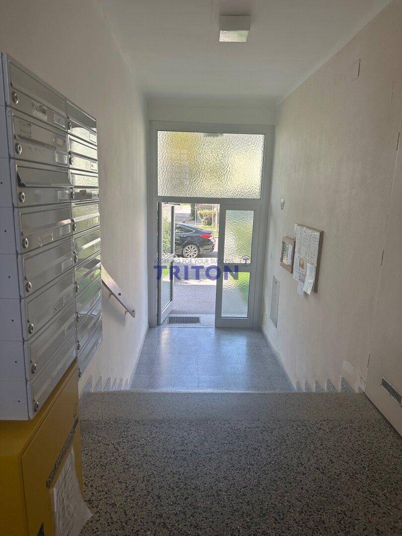 Treppenhaus mit Briefkästen und Blick auf den Haupteingang des Gebäudes.