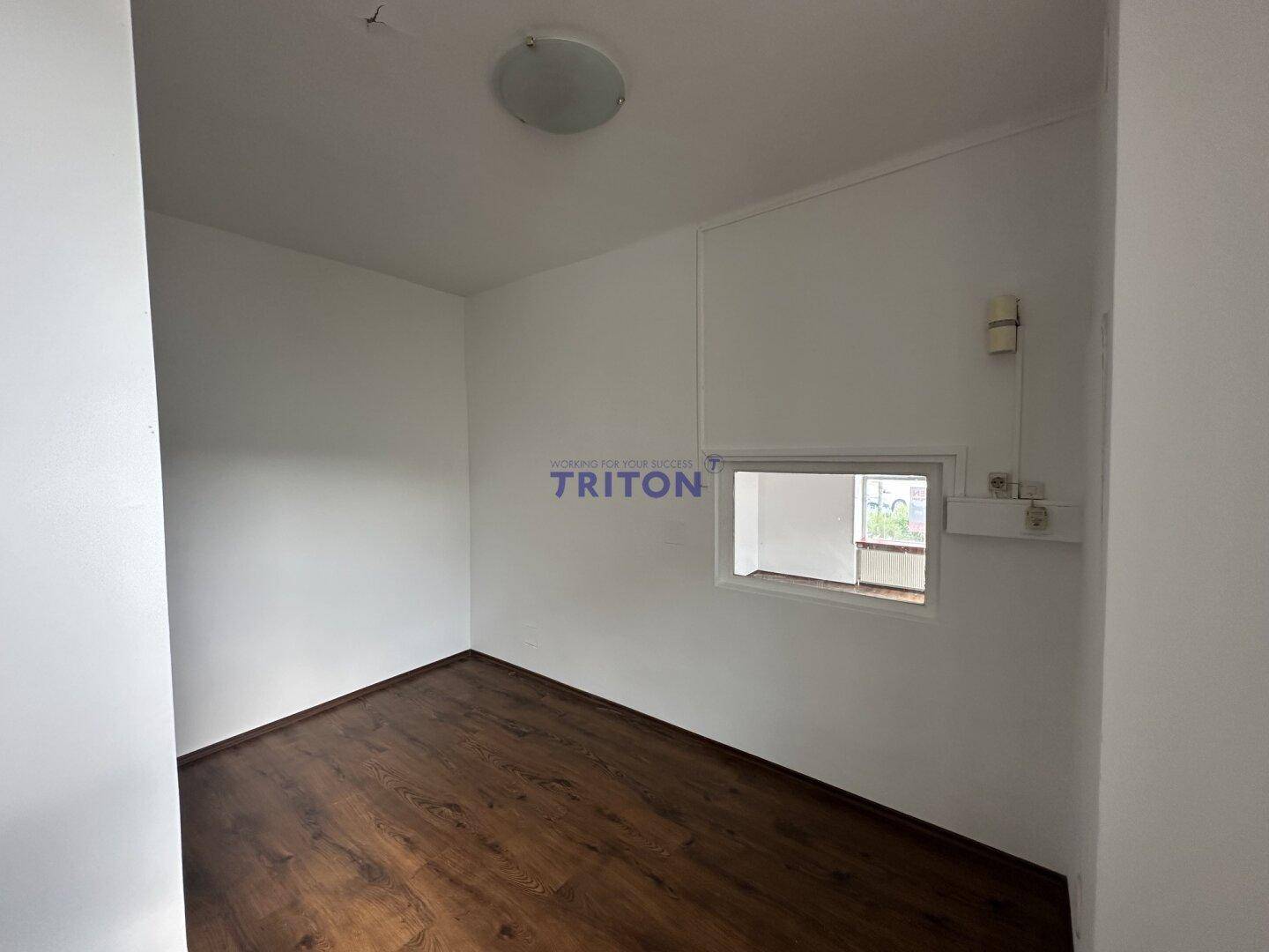 Kleiner, heller Raum mit Laminatboden und einem internen Fenster, ideal als Büro oder Abstellraum.