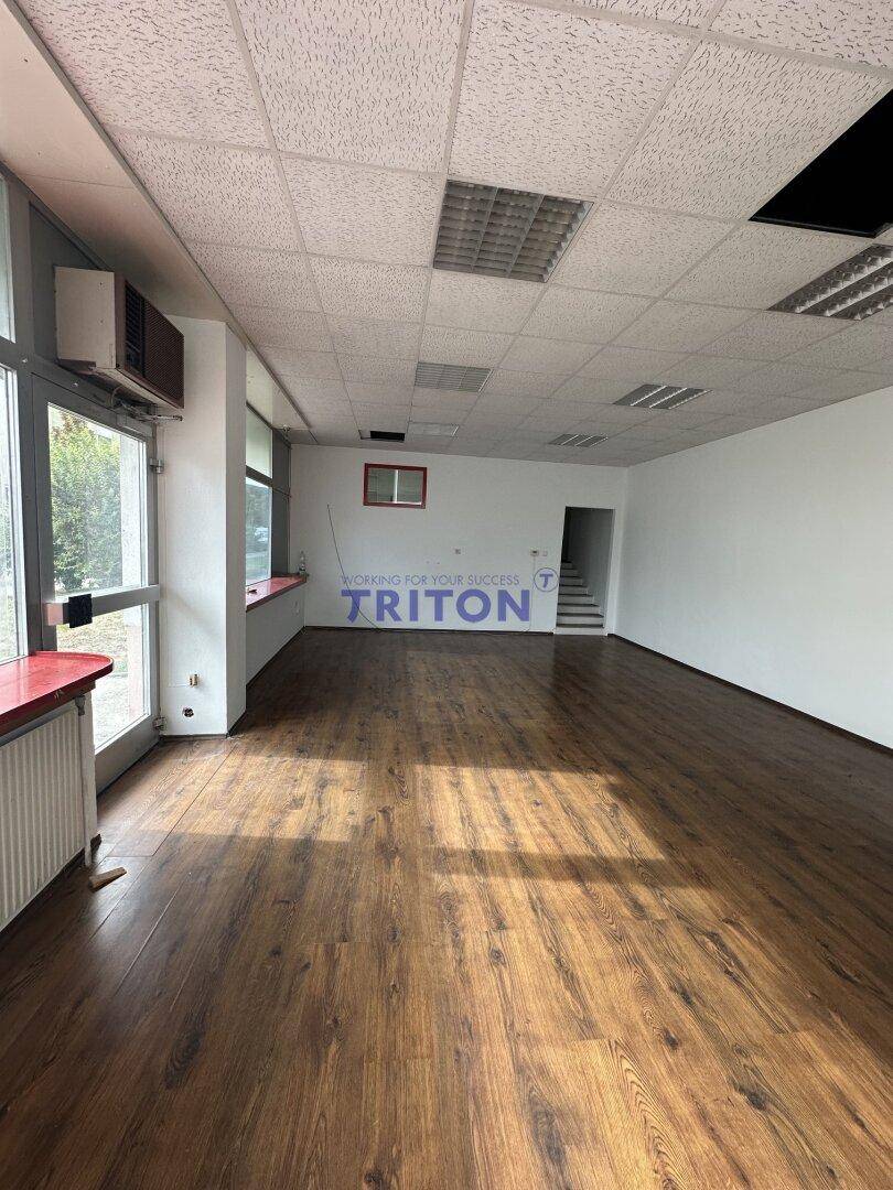Heller Gewerberaum mit Laminatboden, großen Fenstern und einem Zugang zu einer Treppe.