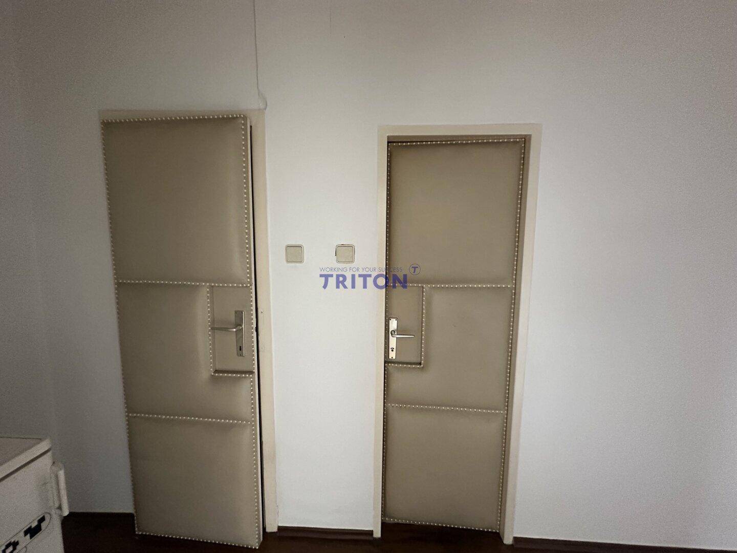 Zwei gepolsterte Türen in einem Flur, die zu verschiedenen Räumen innerhalb der Immobilie führen.