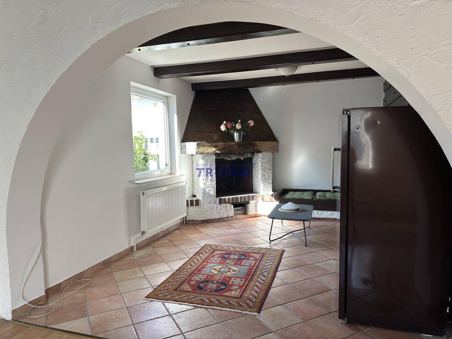 Gemütliches Wohnzimmer mit Kamin, Terrakotta-Fliesenboden und Holzbalken an der Decke.