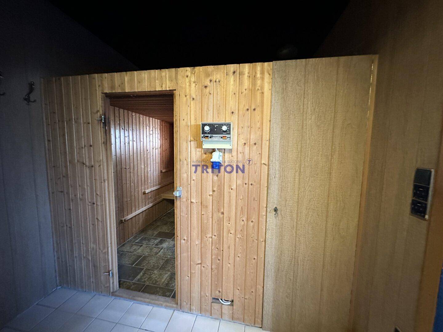 Eingang zur Sauna mit Holzvertäfelung und Steuerungselementen, Teil des Wellnessbereichs.