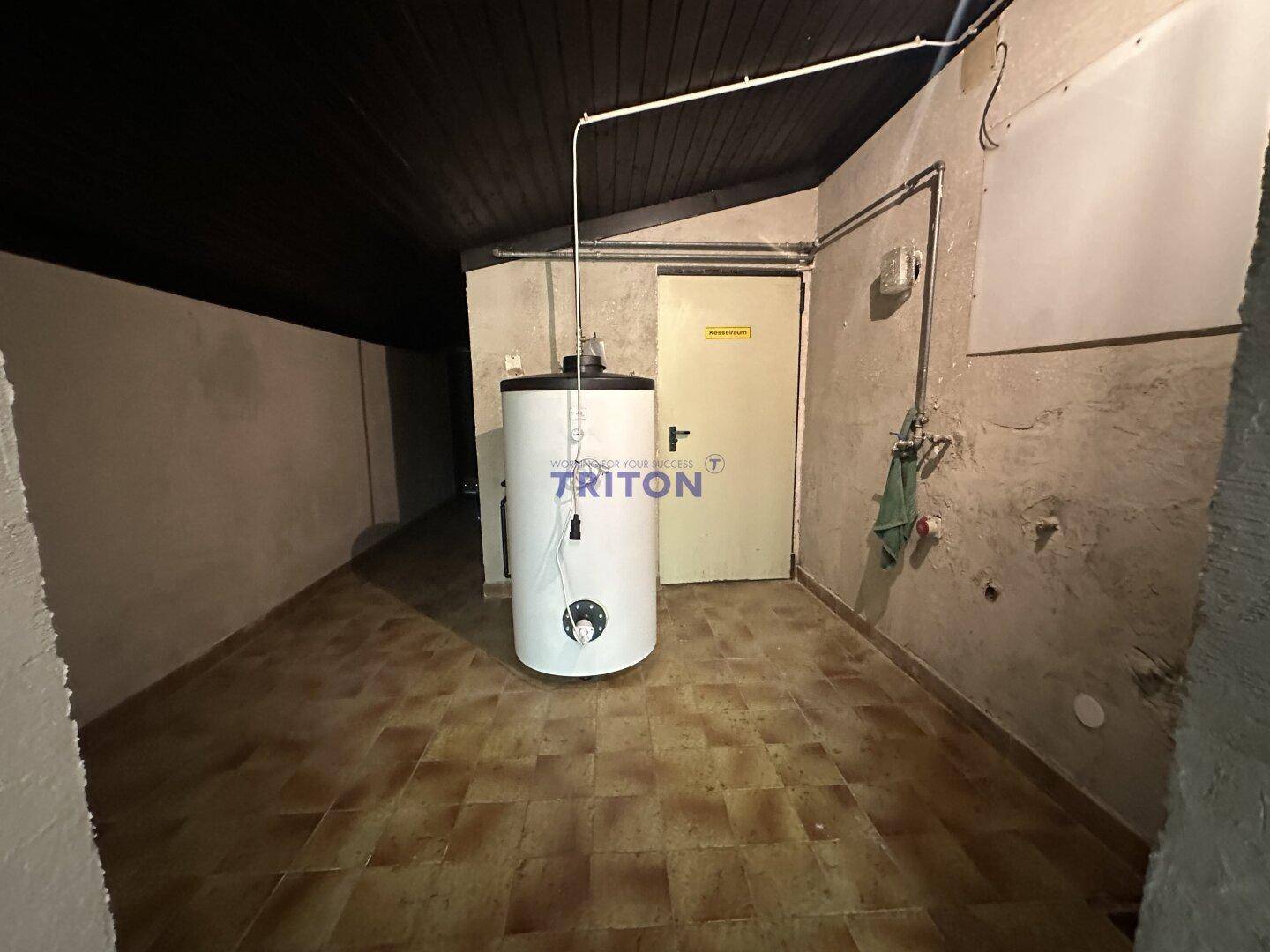 Hauswirtschaftsraum im Keller mit großem Warmwasserspeicher und gefliestem Boden.