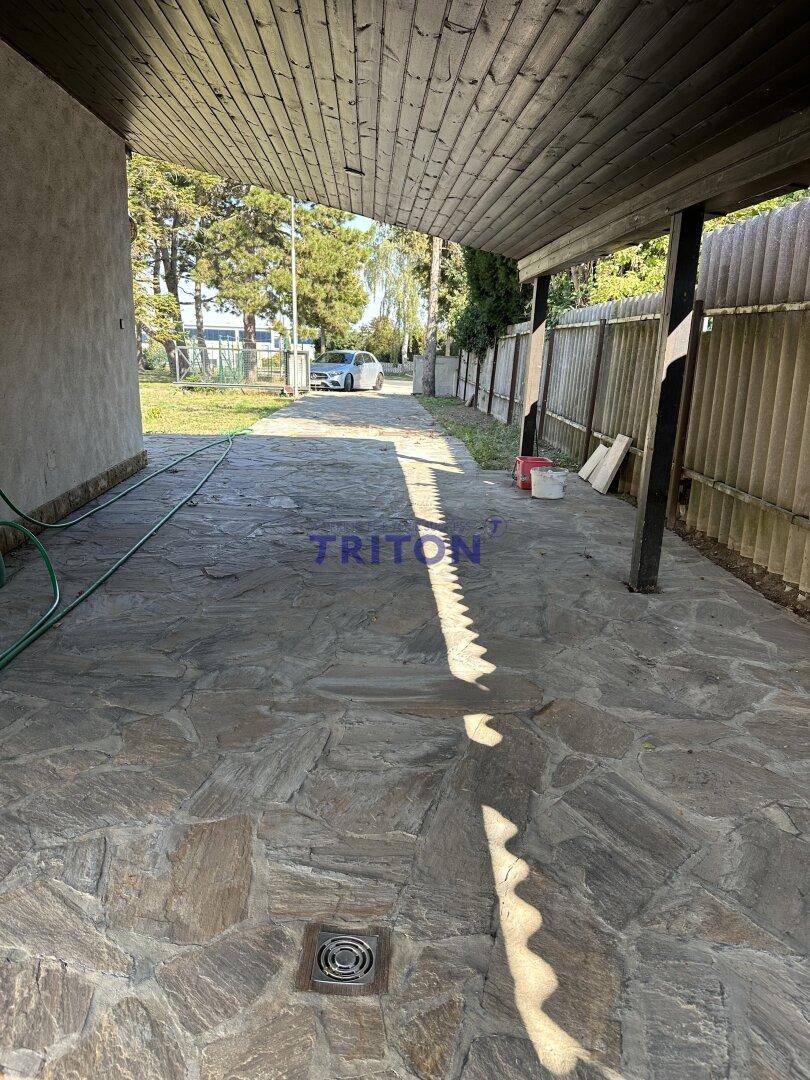 Überdachter Carport-Bereich mit Steinplattenboden und Blick auf die Zufahrt.