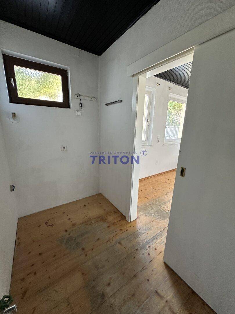 Kleiner Hauswirtschaftsraum mit Holzfußboden, Fenster und Schiebetür.