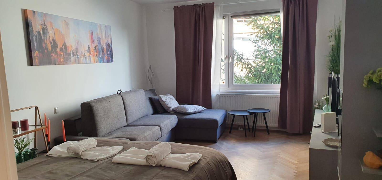 Helles Wohnzimmer mit Sofa, Fenster und Blick ins Grüne.