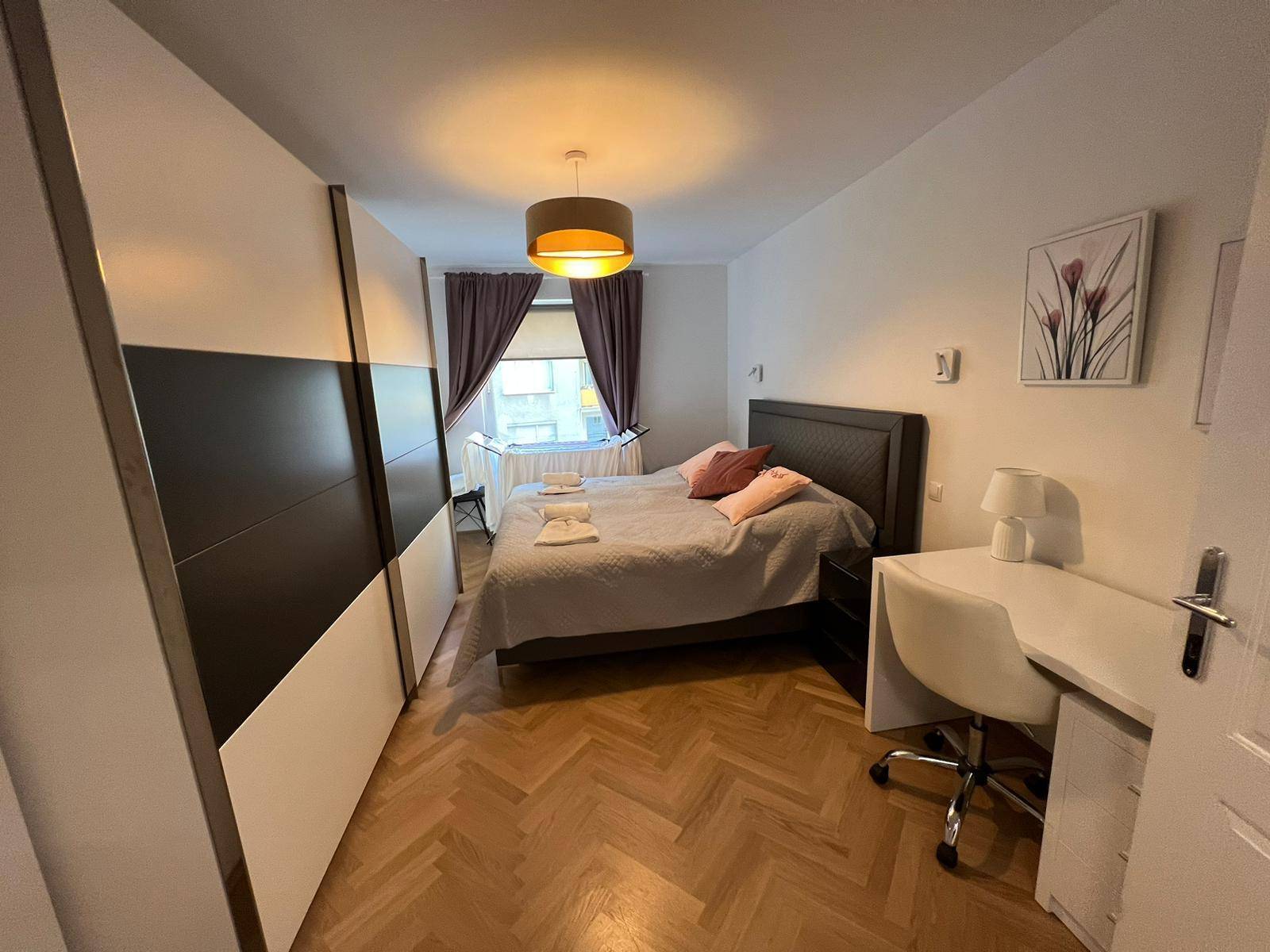 Schlafzimmer mit Doppelbett, großem Kleiderschrank und Schreibtisch.