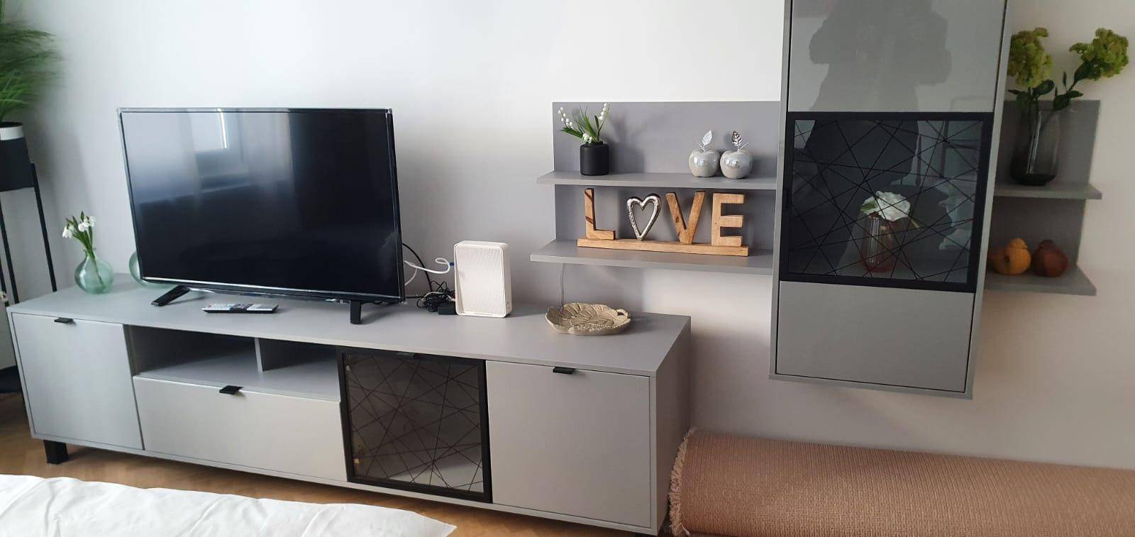 Detailansicht des Wohnzimmers mit TV, Regal und Dekoration.