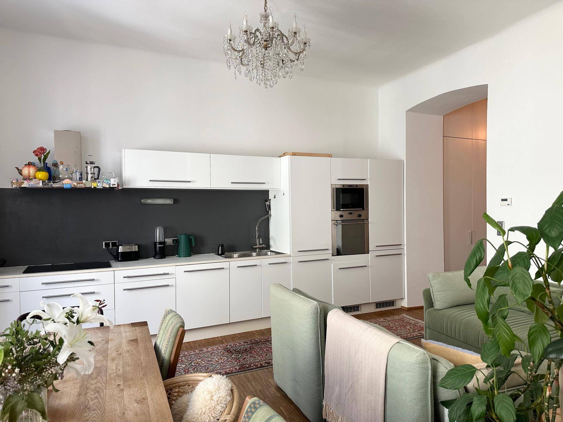Helle, moderne Einbauküche mit weißen Schränken, integrierten Geräten und offenem Übergang zum Wohnbereich.