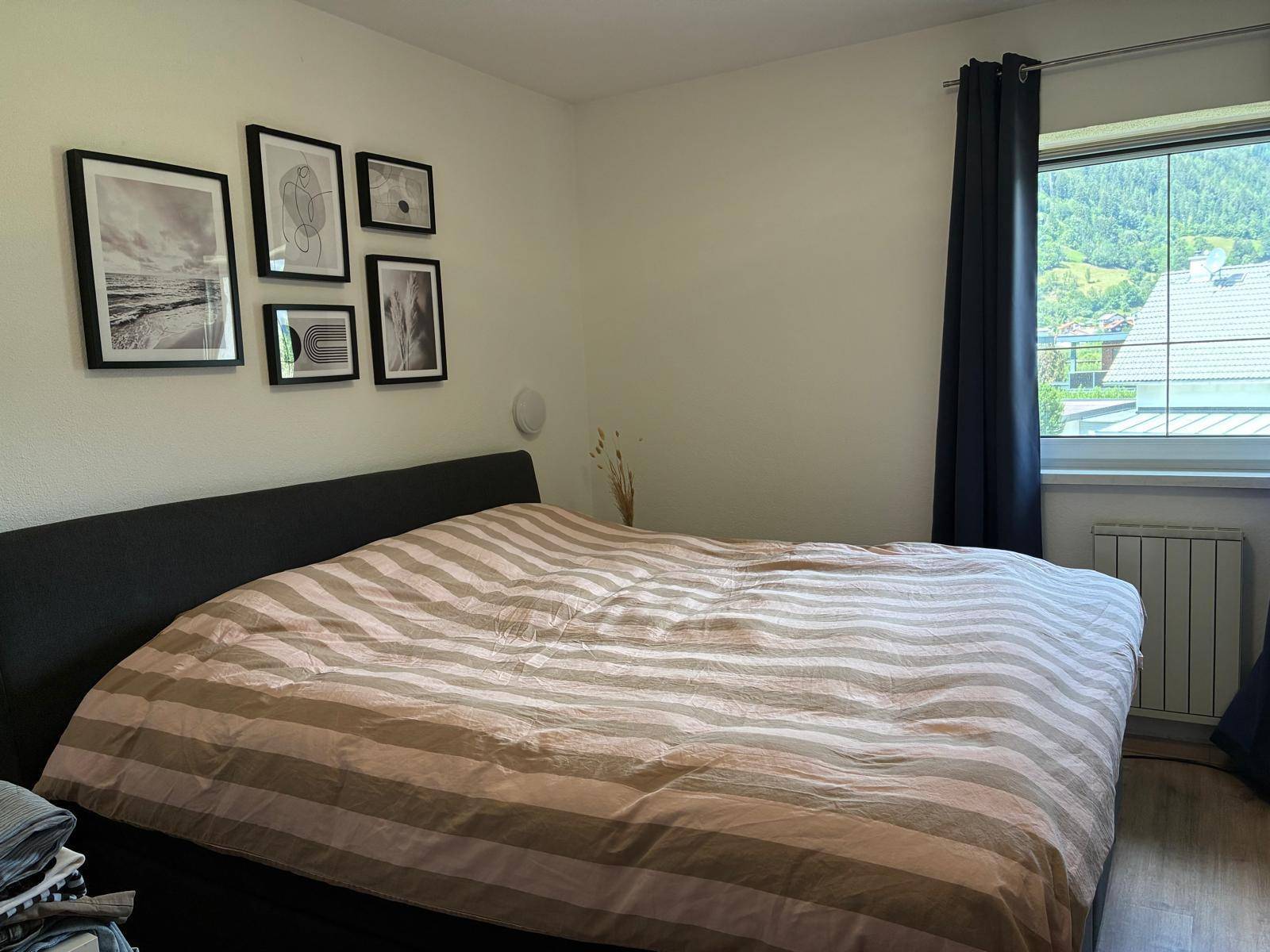 Schlafzimmer mit Doppelbett, gerahmten Bildern an der Wand und einem schönen Blick auf die Berge.