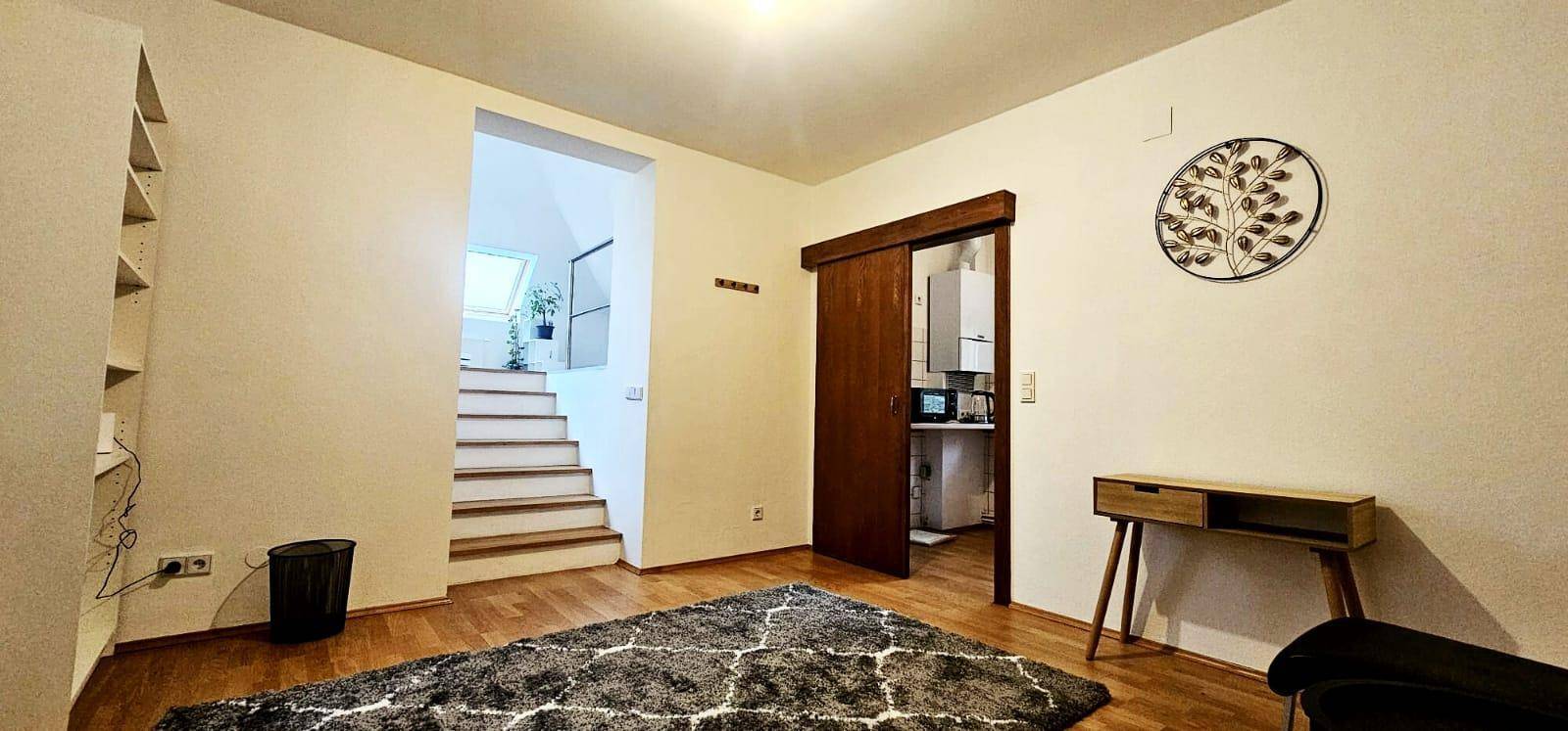 Heller Flur mit Holztreppe und Teppich, der zu weiteren Räumen führt.