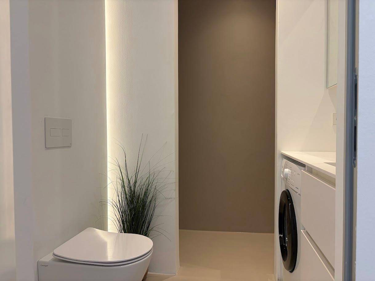 Modernes WC mit wandhängender Toilette und dezenter Beleuchtung, Teil eines funktionalen Badezimmers.