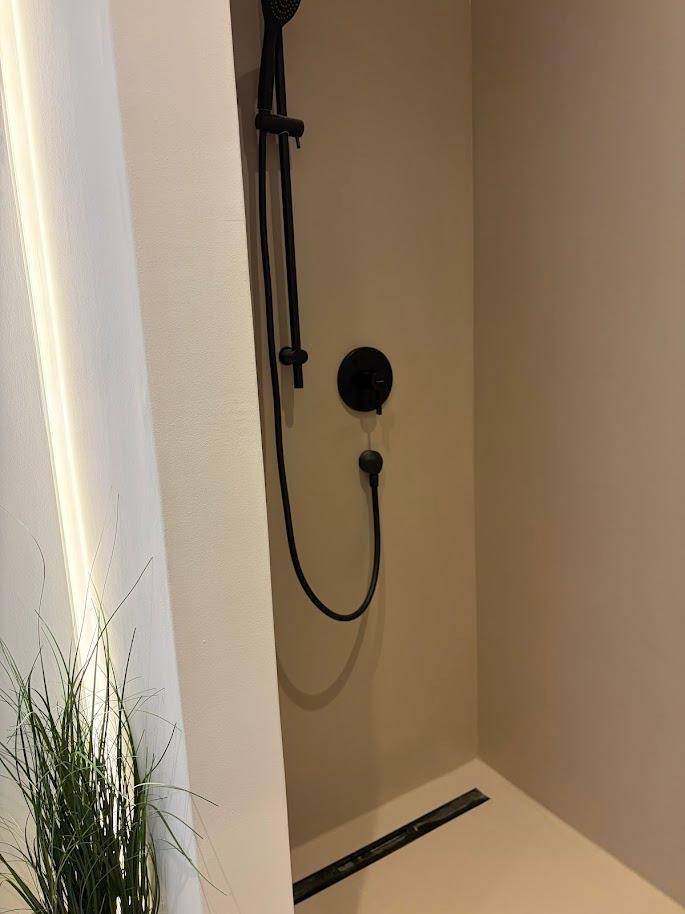 Moderne Duschkabine mit schwarzen Armaturen und bodengleichem Zugang in einem hellen Badezimmer.