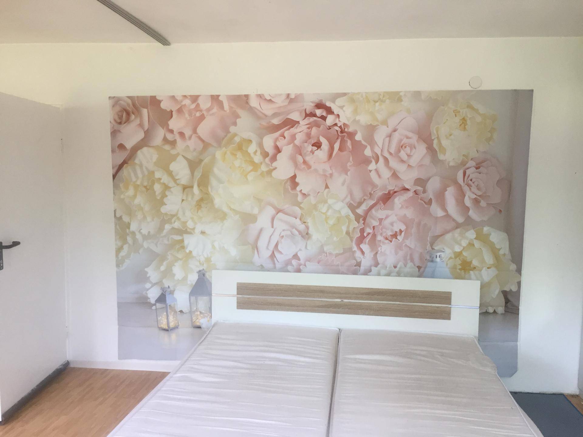 Schlafzimmer mit großem Blumenwandbild und schlichtem Doppelbett.