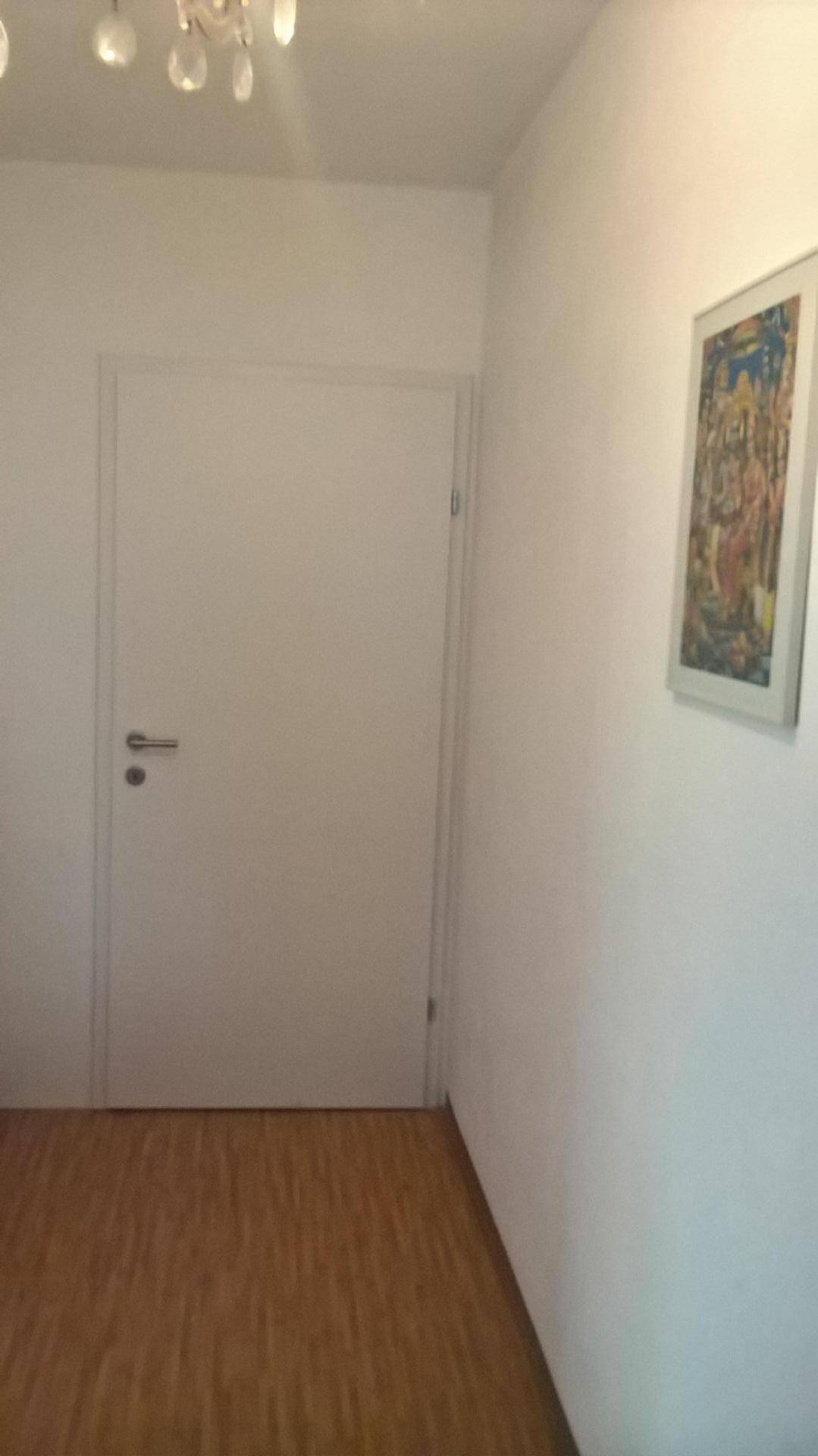 Heller Flur mit Holzboden und einer schlichten weißen Tür.