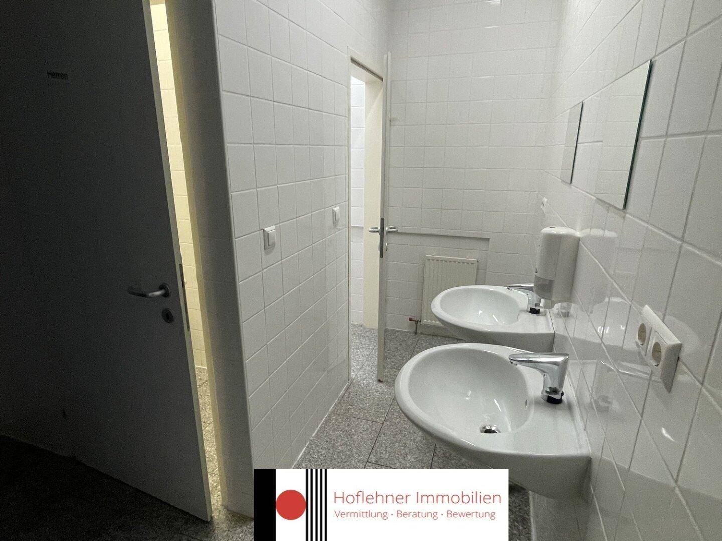 Sanitärbereich mit zwei Waschbecken und weißen Fliesen, funktional und in gutem Zustand.
