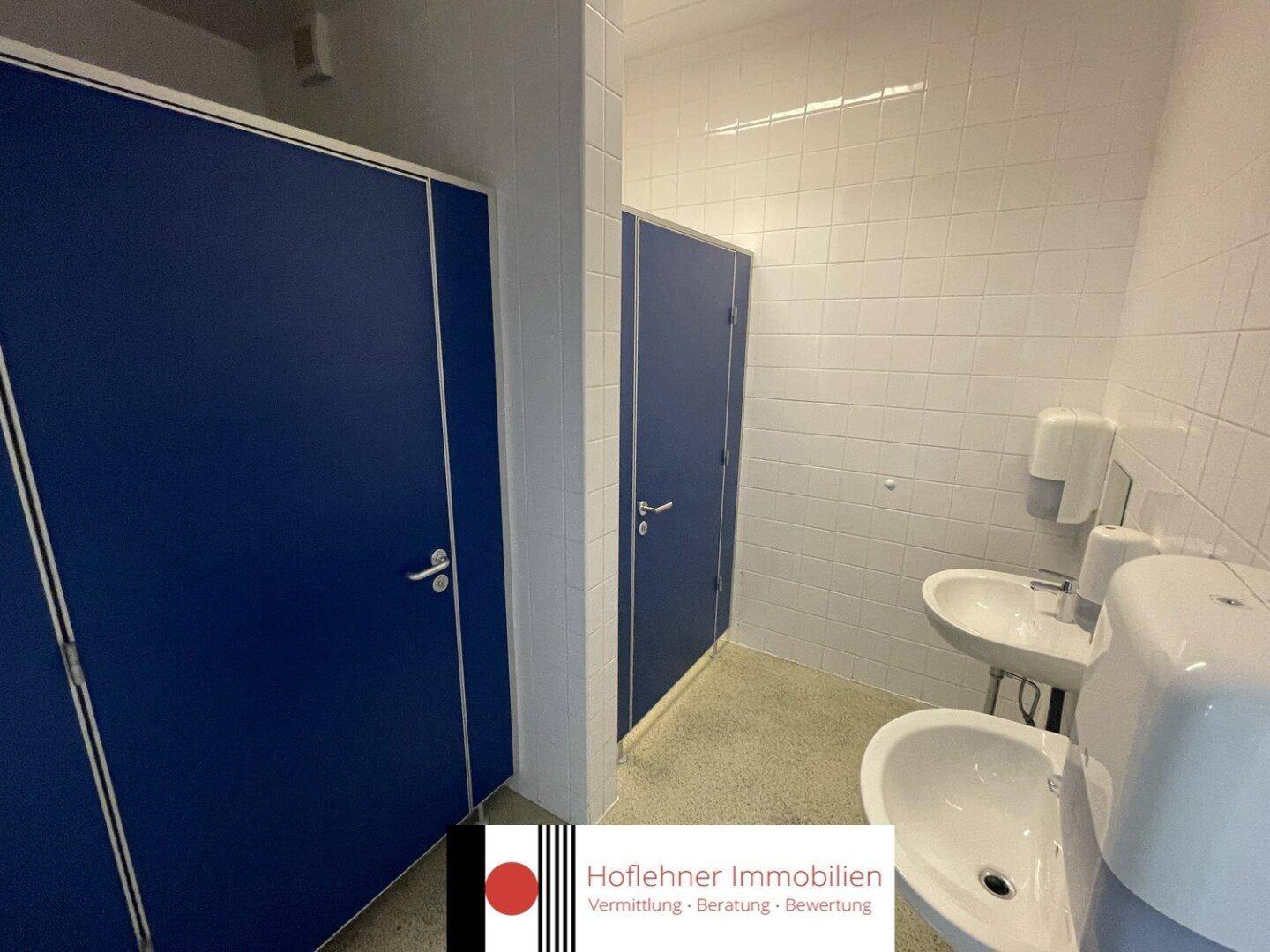 Sanitärbereich mit blauen Kabinentüren und Waschbecken, sauber und funktional ausgestattet.