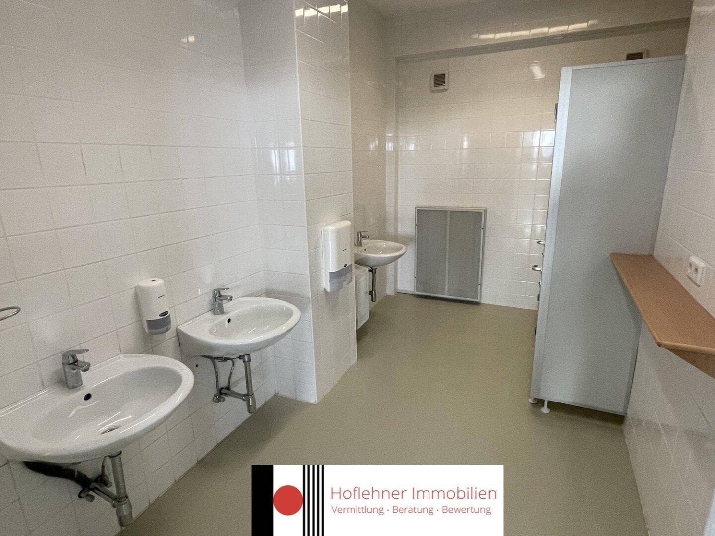Sanitärbereich mit mehreren Waschbecken und weißen Fliesen, gut gepflegt und funktional.