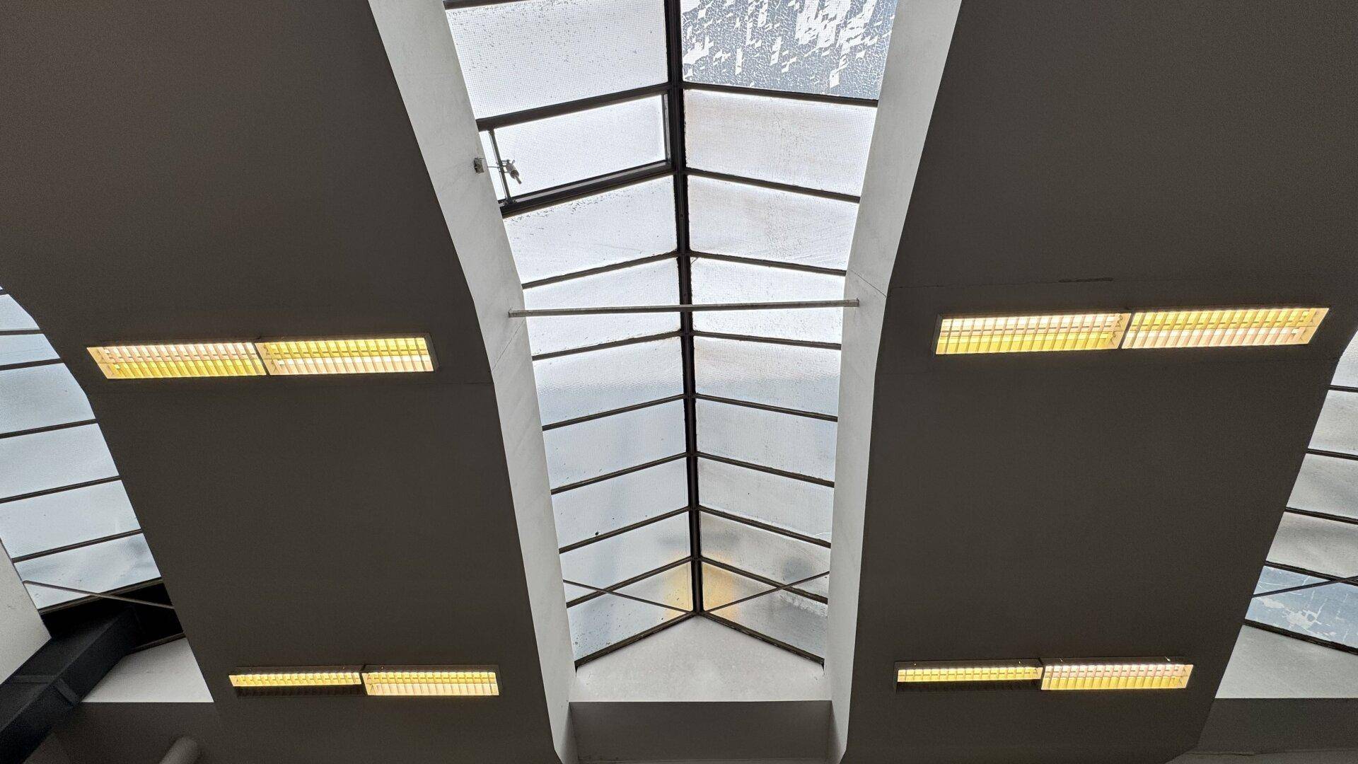 Dachfenster und lange Leuchtstofflampen sorgen für eine helle und gut ausgeleuchtete Atmosphäre in der Industriehalle.