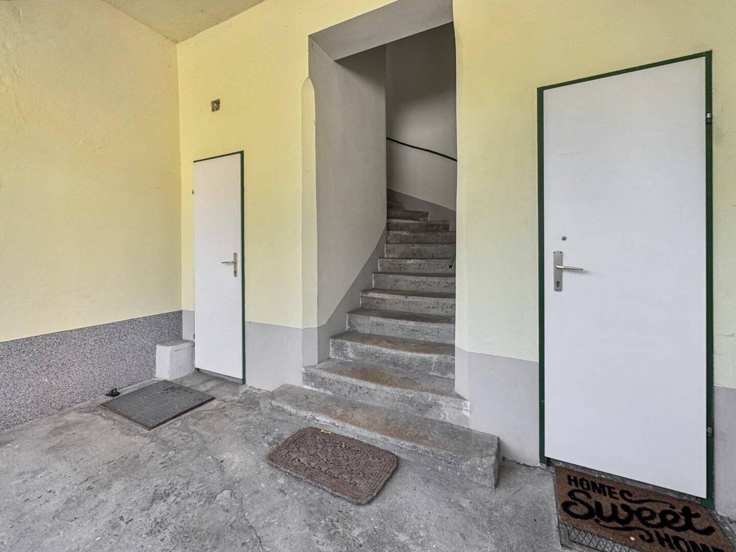 Eingangsbereich mit einer Steintreppe und zwei Türen, die zu den einzelnen Wohneinheiten führen.
