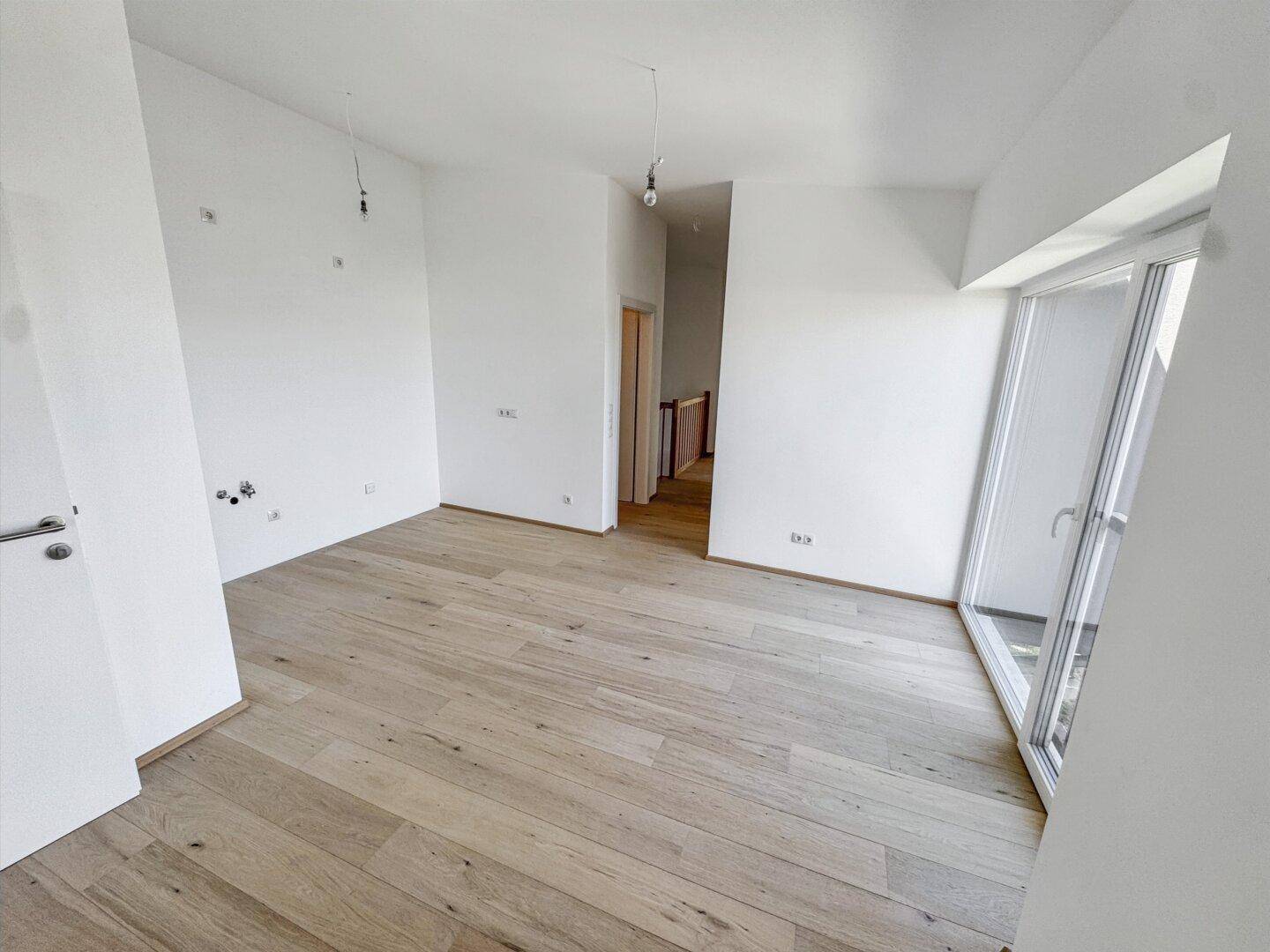 Helles Schlafzimmer mit Holzboden und Zugang zu einem weiteren Raum, ideal für Ruhe.