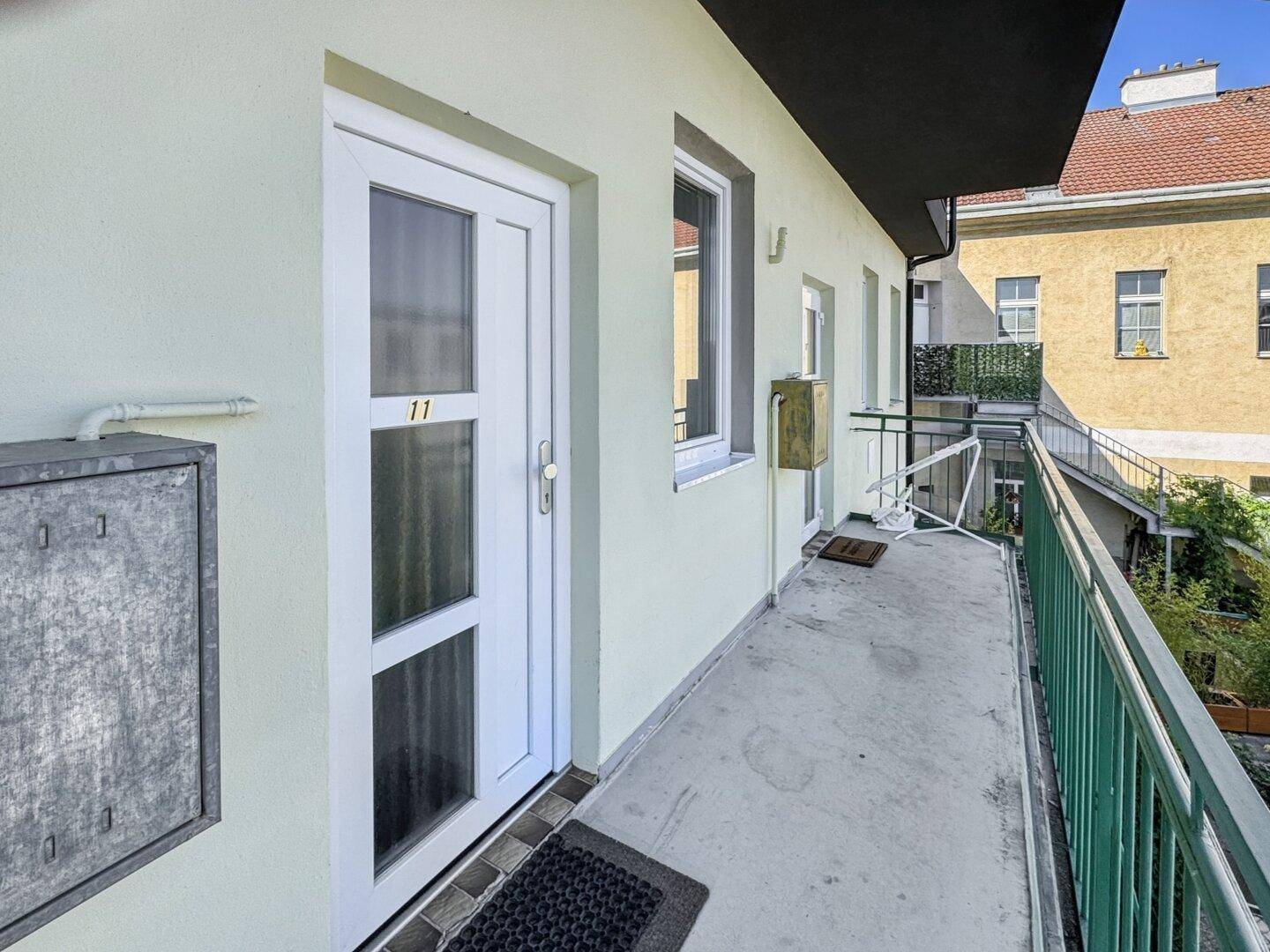 Schmaler Balkon mit Metallgeländer und Blick auf die Umgebung, zugänglich über eine Tür.