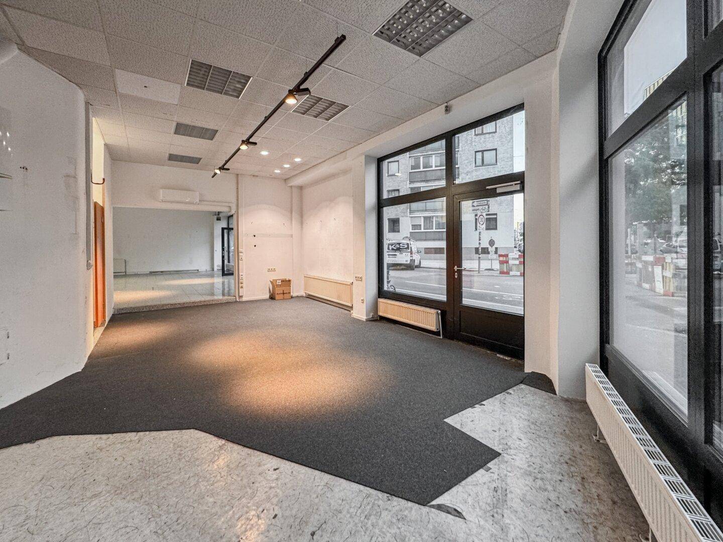 Heller Gewerberaum mit Teppichboden und großen Fenstern zur Straße, ideal für ein Geschäft.