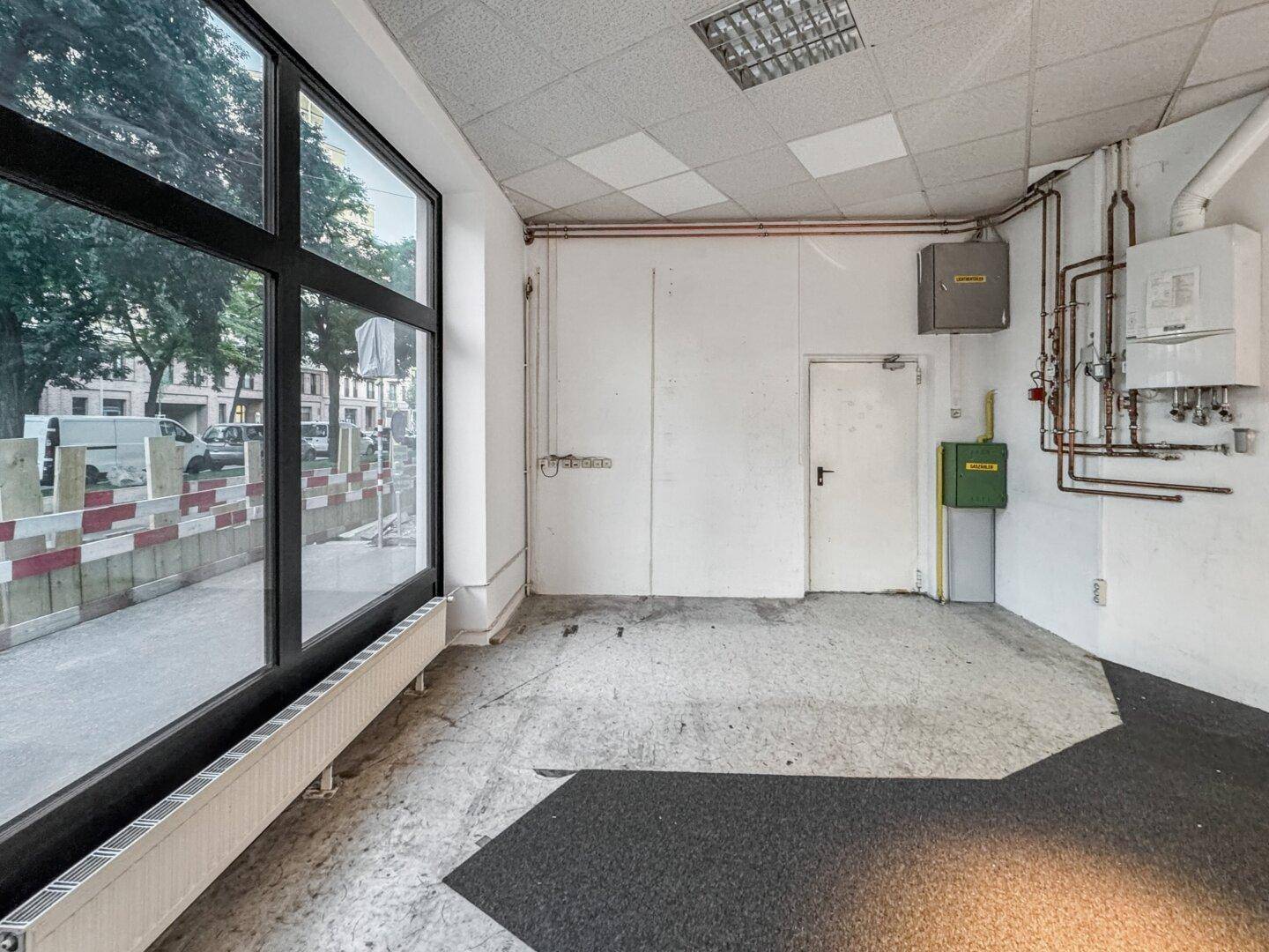 Technikraum mit Heizungsanlage, Leitungen und elektrischen Installationen, angrenzend an den Hauptraum.