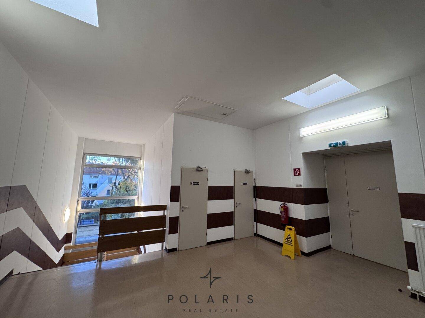 Geräumiger Treppenabsatz mit mehreren Türen, einem Fenster und einem Oberlicht, das für viel natürliches Licht sorgt.