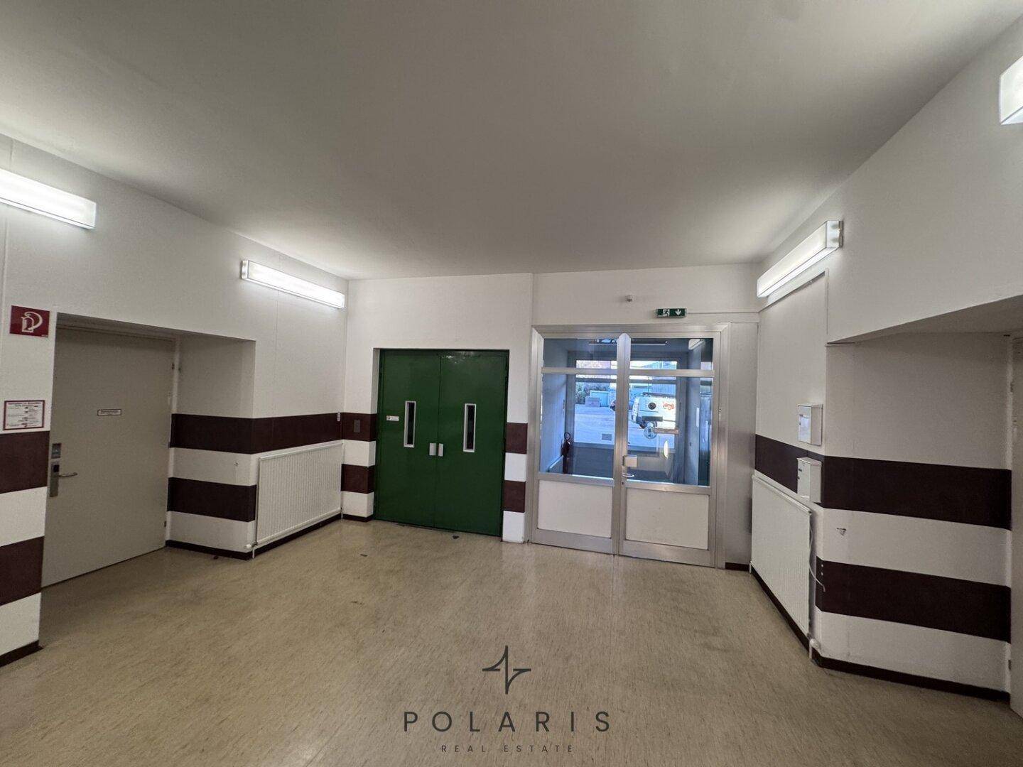 Heller Eingangsbereich mit Glastüren, weiteren Türen und Heizkörpern, der einen einladenden Zugang bietet.