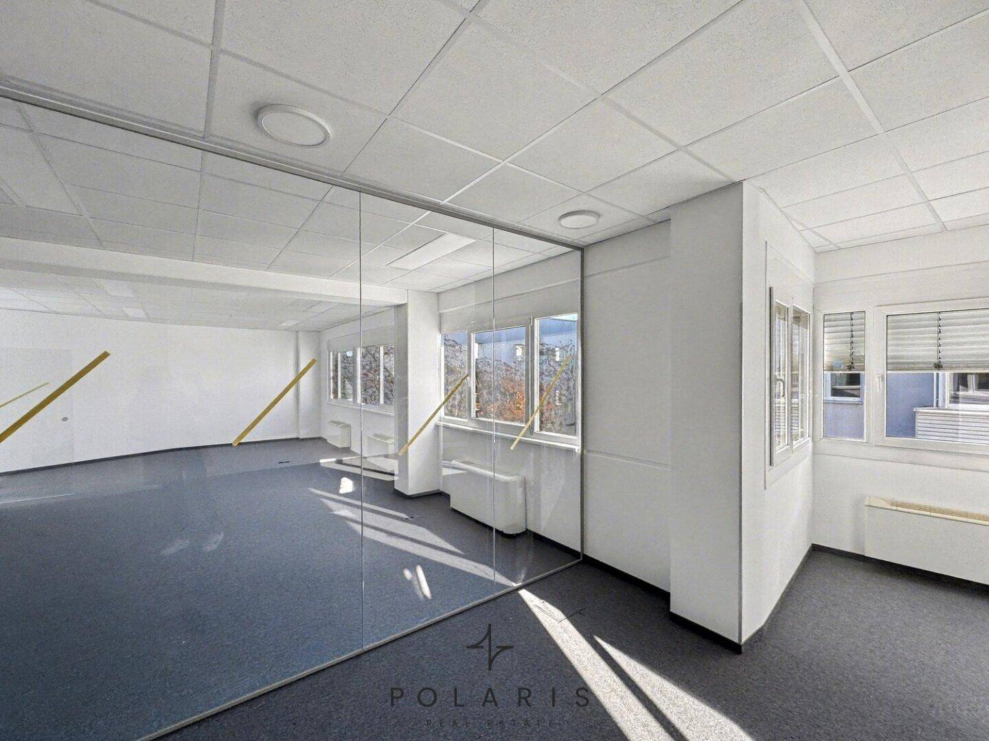 Geräumiges, leeres Büro mit Teppichboden und modernen Glaswänden, bereit zur individuellen Gestaltung.