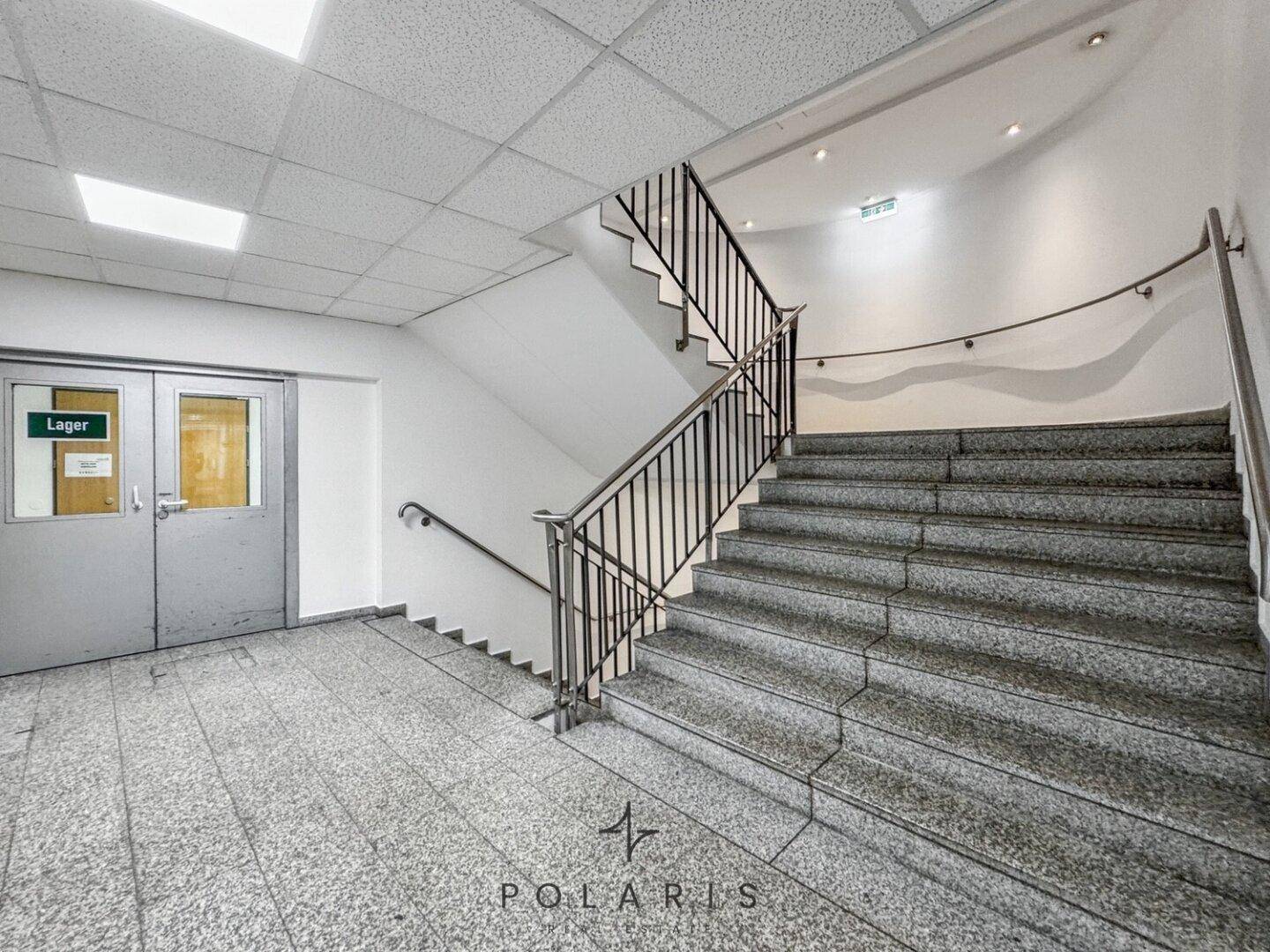 Geräumiges Treppenhaus mit Granitstufen und Metallgeländer, das zu weiteren Etagen führt.