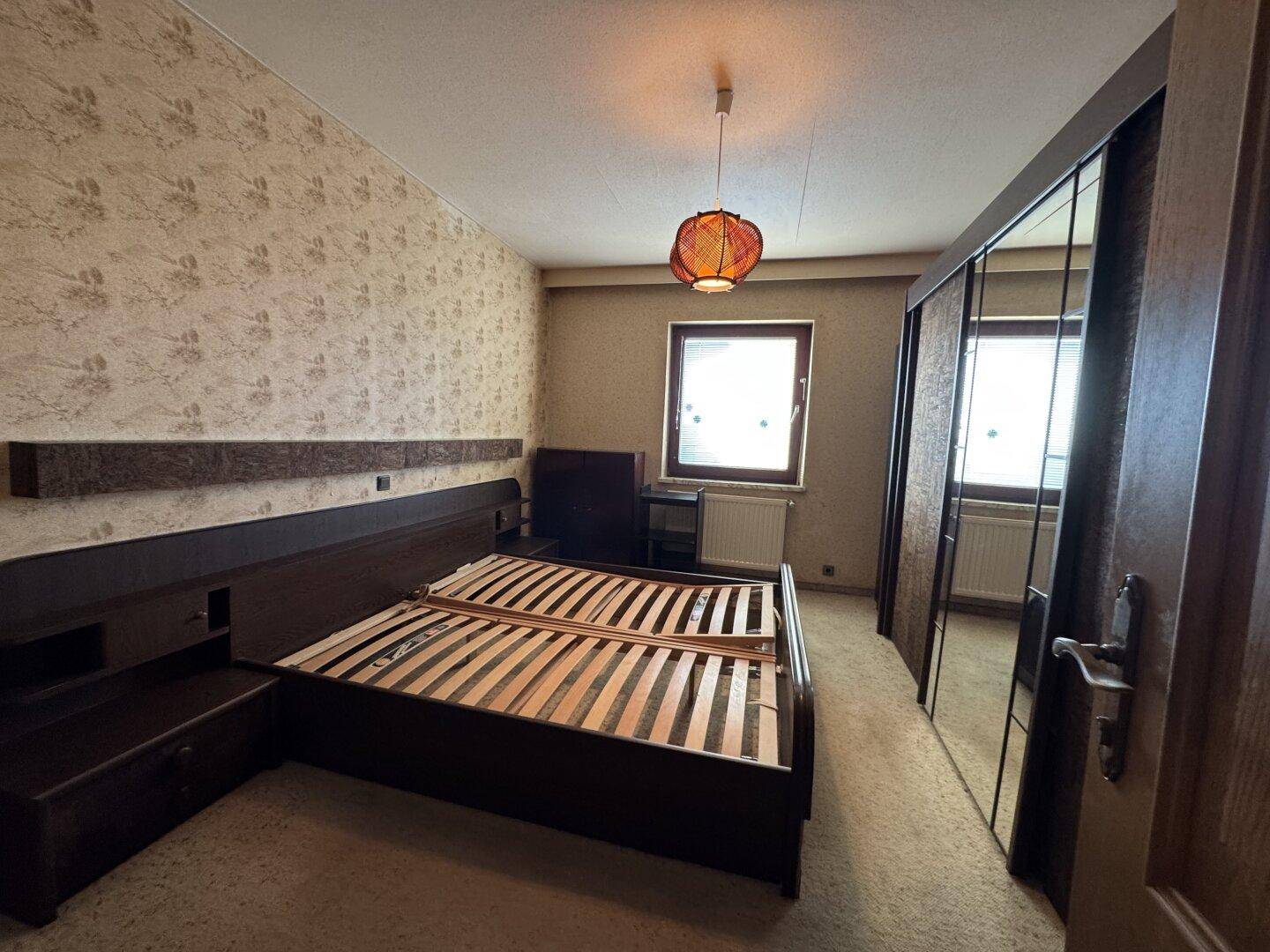 Geräumiges Schlafzimmer mit Doppelbett, Spiegelschrank und Fenster für Tageslicht.