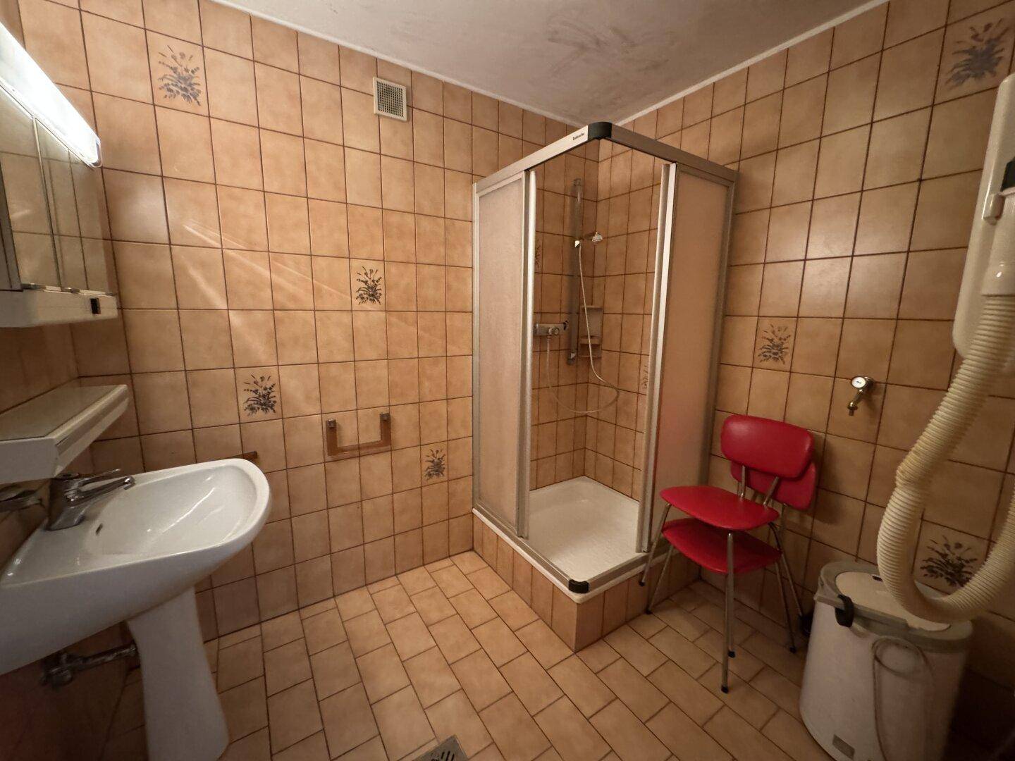 Badezimmer mit Duschkabine, Waschbecken und braunen Fliesen im traditionellen Stil.
