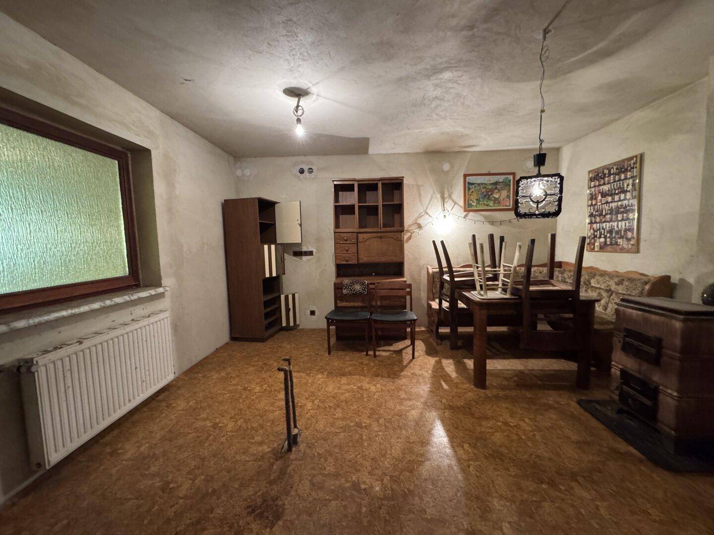 Geräumiger Kellerraum mit Fenster, Holzboden und Platz für verschiedene Nutzungen.