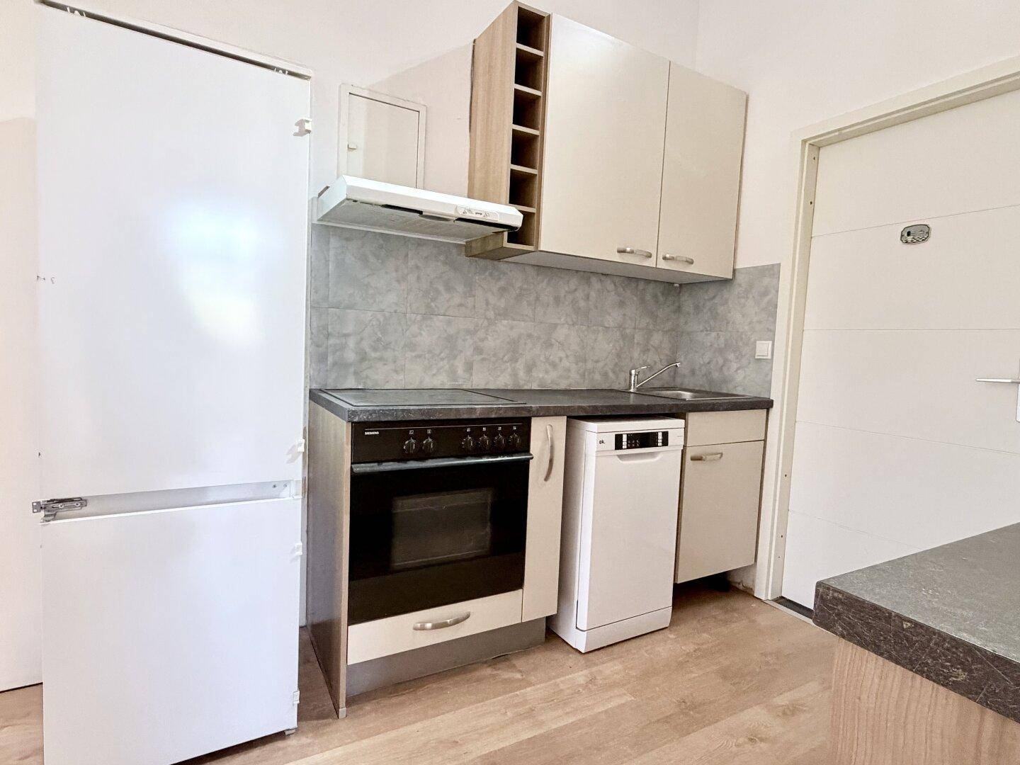 Kompakte Einbauküche mit Kühlschrank, Herd und Spülmaschine, ideal für kleine Haushalte.