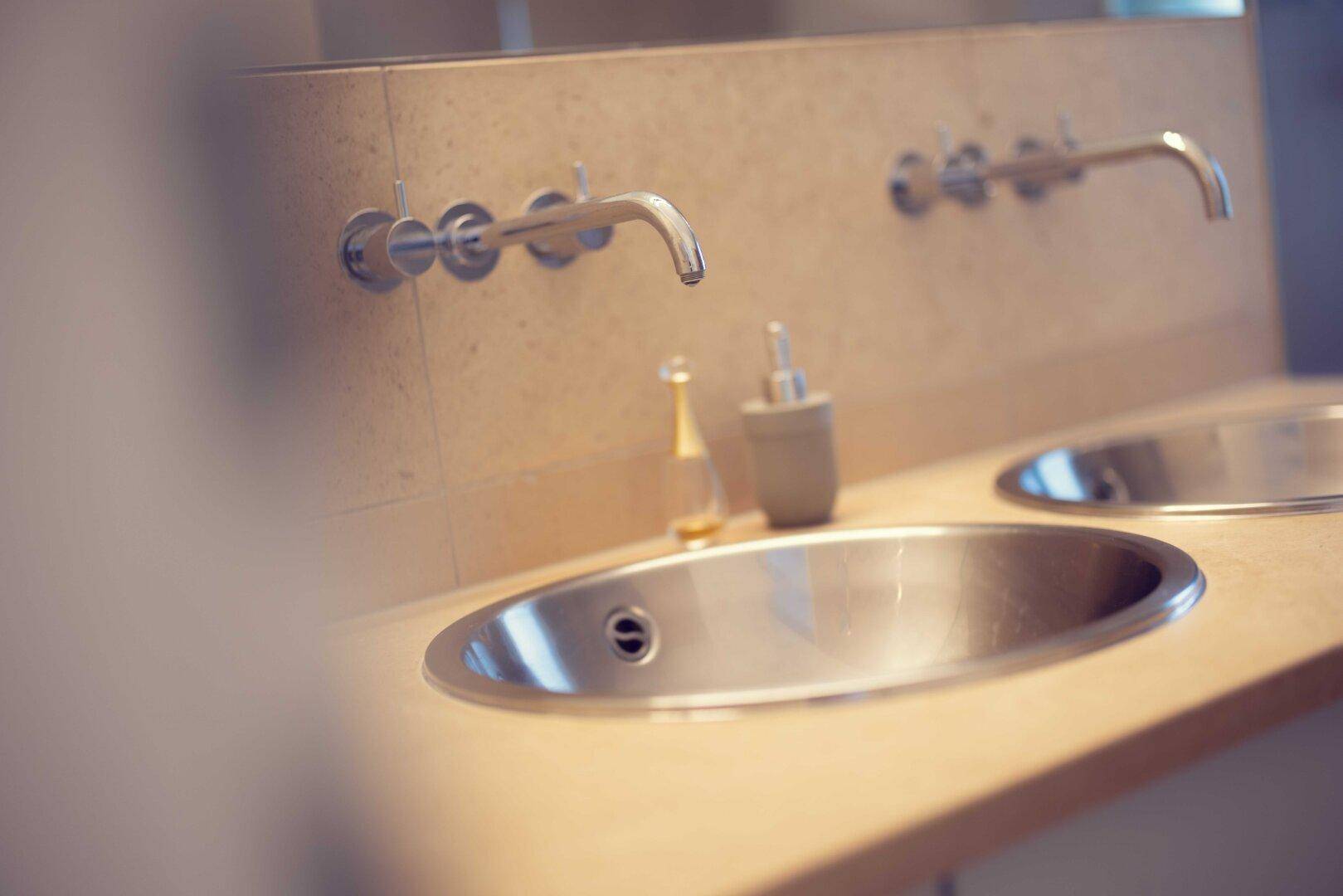 Detailaufnahme eines modernen Einbauwaschbeckens mit Wandarmatur im Badezimmer.