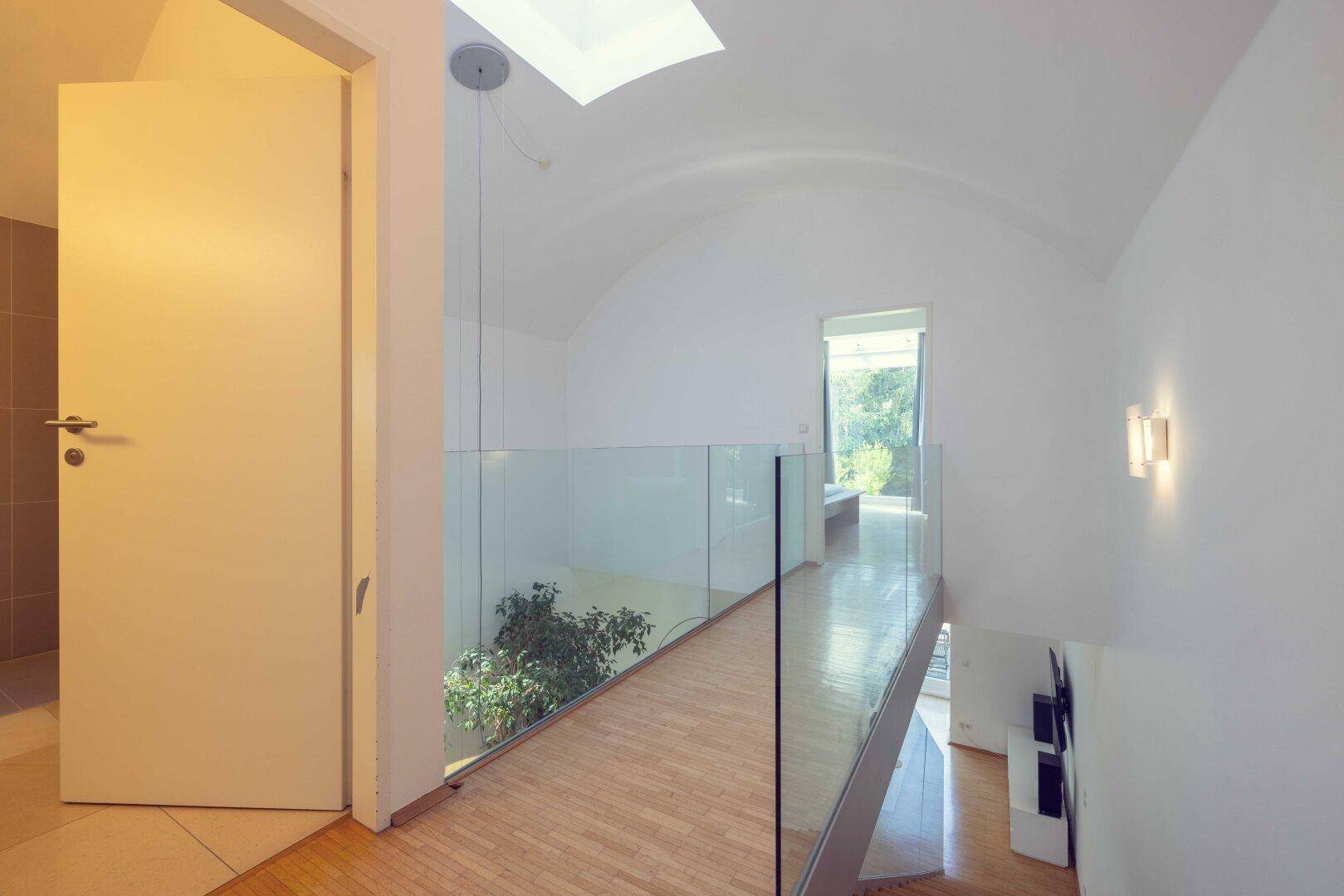 Heller Flur im Obergeschoss mit Glasgeländer, Gewölbedecke und Oberlicht.