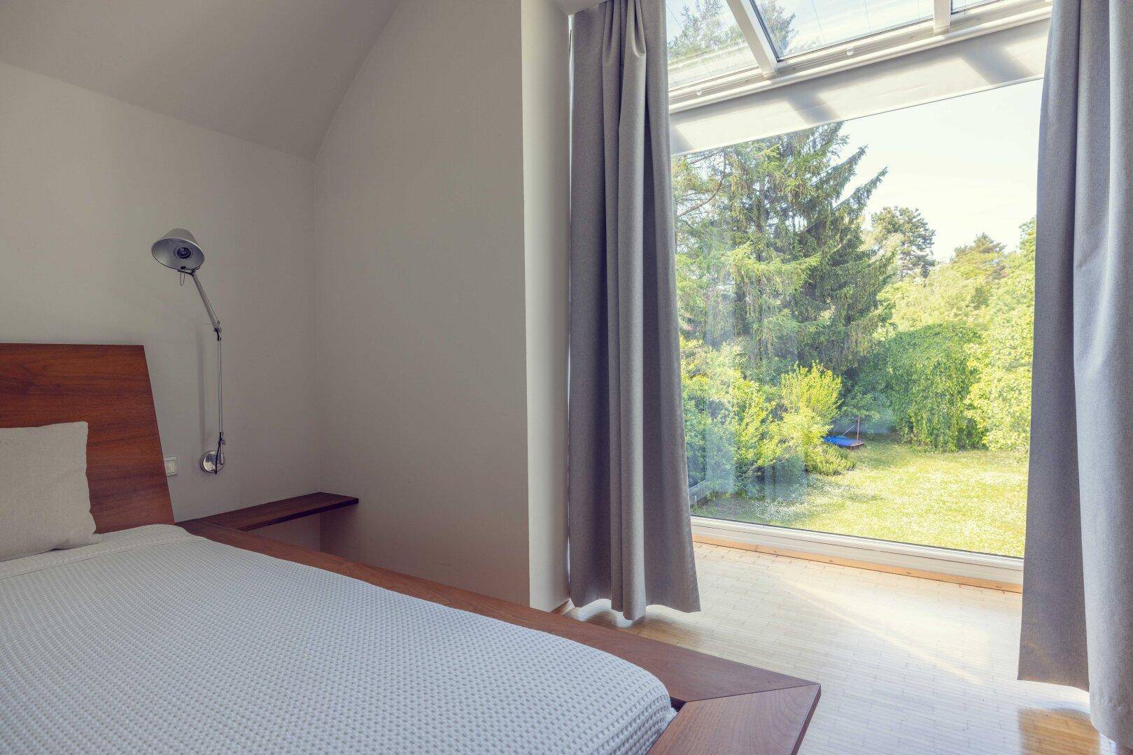 Großes Fenster im Schlafzimmer mit weitem Blick auf die grüne Umgebung.